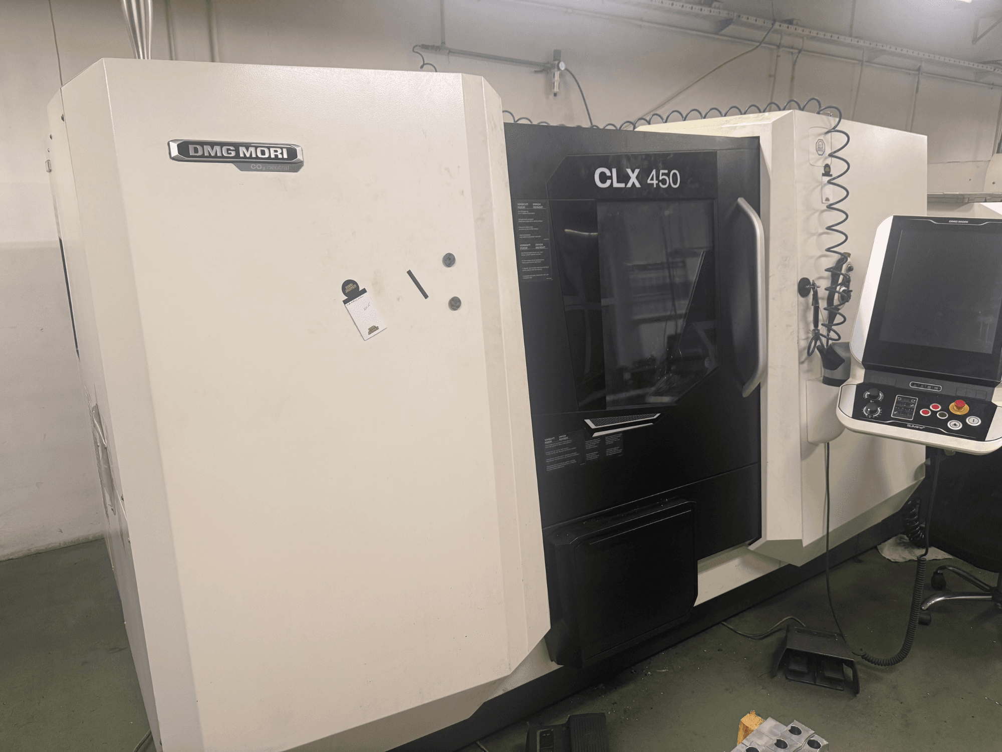 Machine CNC DMG MORI CLX 450, vue latérale avec panneau de commande, boutons opérationnels visibles et espace de travail propre.