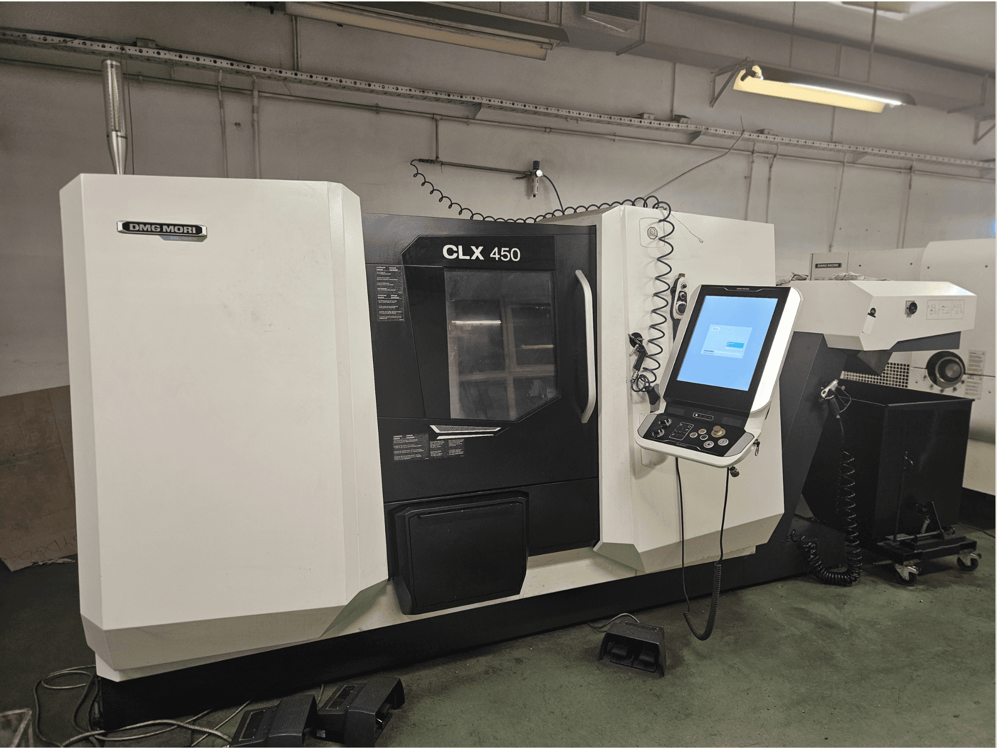 Machine CNC DMG MORI CLX 450 vue de face, dotée d'un panneau de commande et d'un écran tactile, dans un environnement d'atelier.