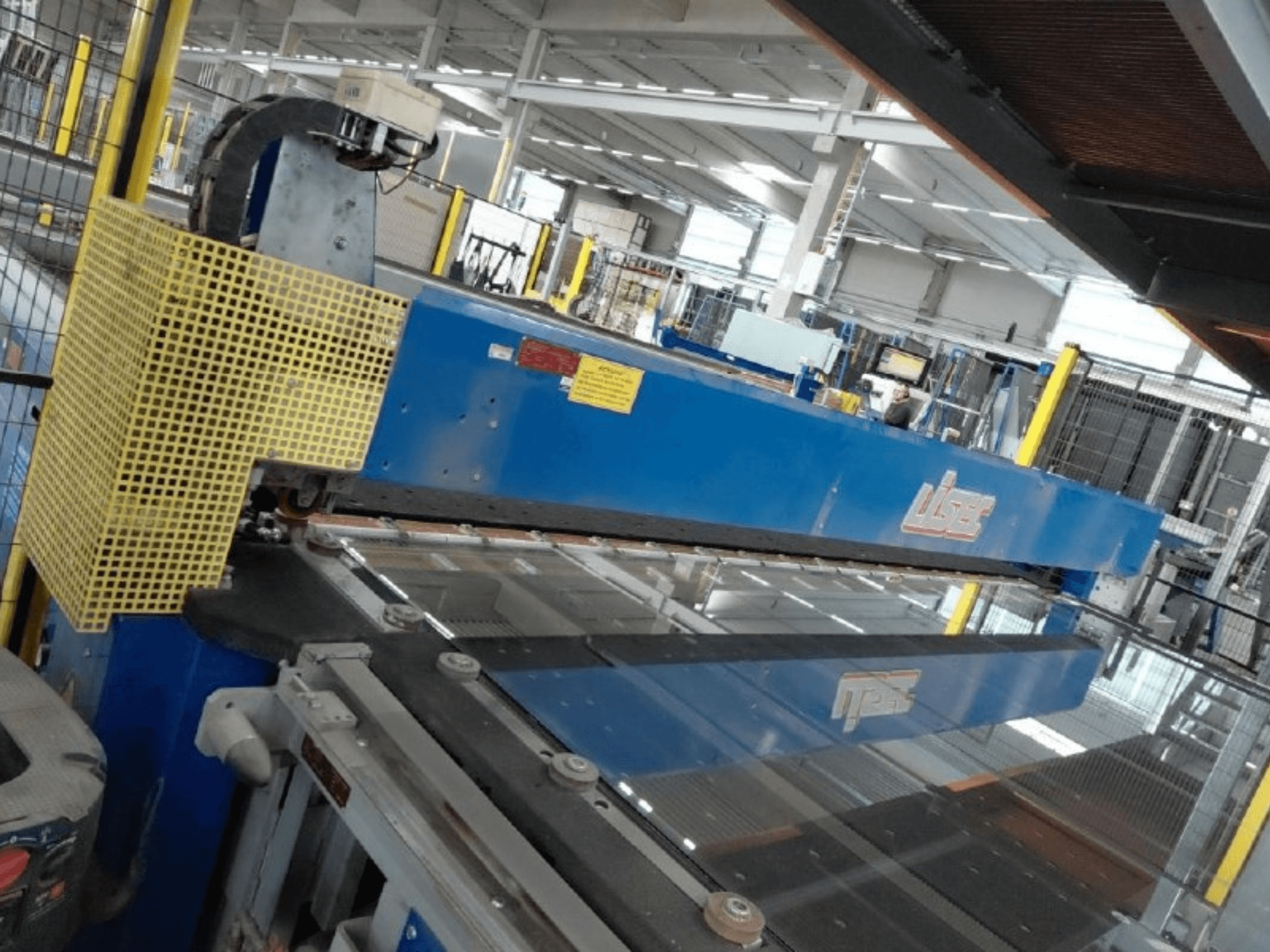 Vue de face de la ligne de découpe combinée LISEC pour verre feuilleté de sécurité (VSG) et verre flotté, équipée d'un outil de découpe bleu et d'un treillis de protection.