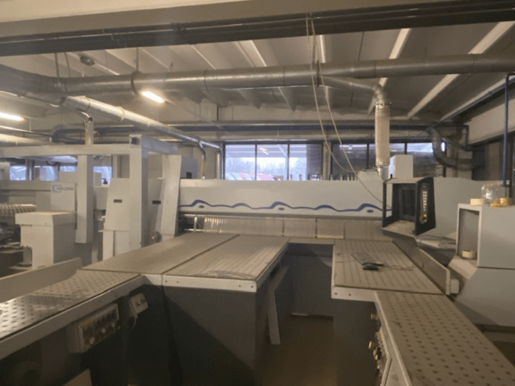 Espace de travail industriel comprenant une installation de machines et un panneau de commande, vu d'un angle frontal surélevé.