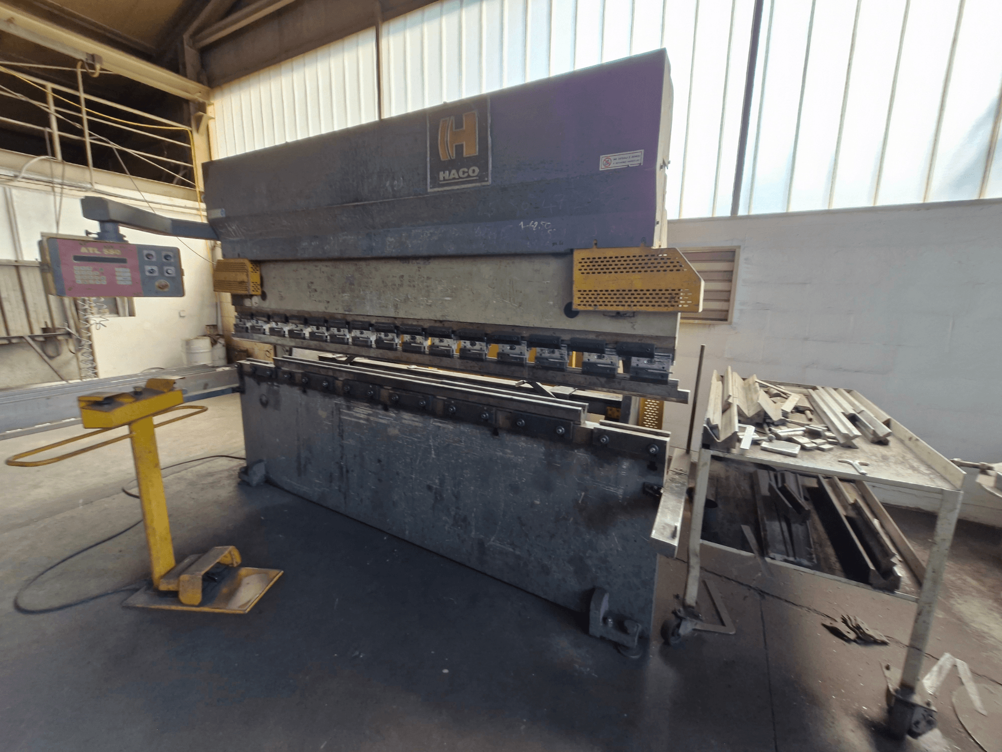 Presse plieuse HACO PPM 30135 b dans un atelier, vue de face montrant le panneau de commande et la ferraille sur une table à côté.