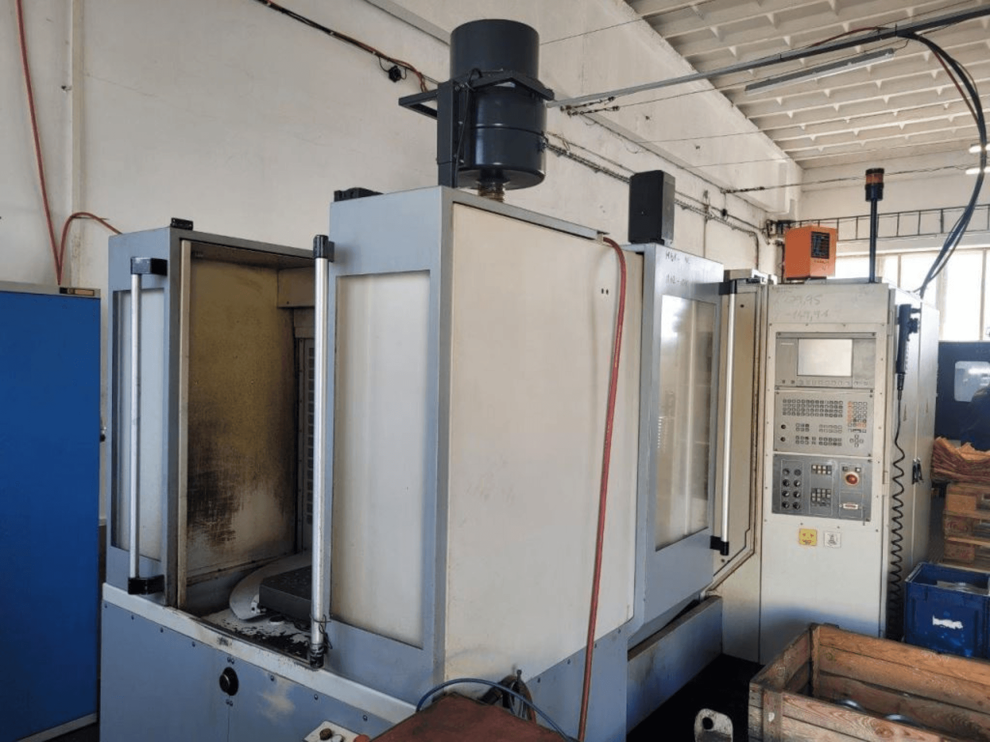 Fraiseuse industrielle à commande numérique avec panneau de commande, vue latérale, montrant le boîtier et les salissures visibles sur les surfaces.