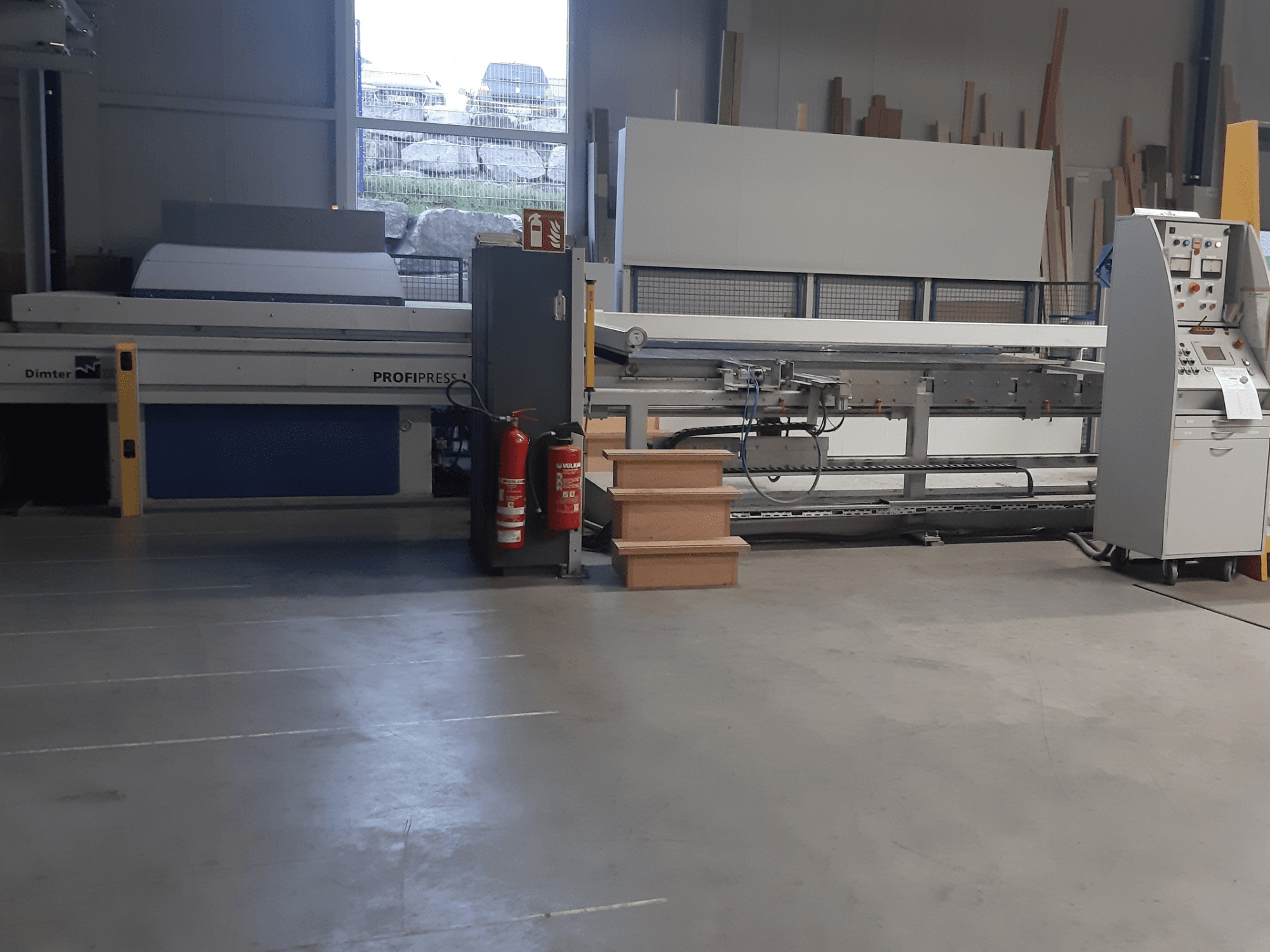 Machine Dimter ProfiPress dans un atelier, vue de face, avec le panneau de commande et les extincteurs à proximité.