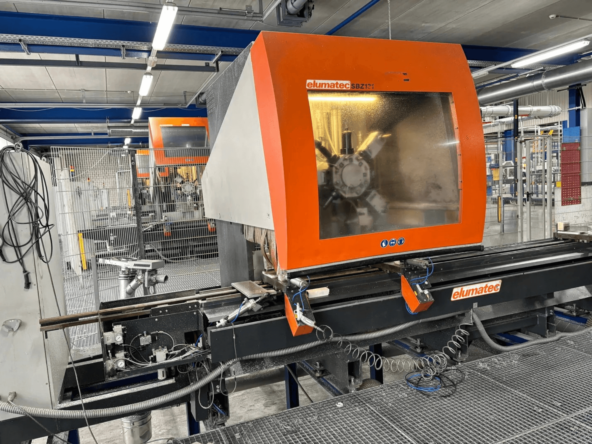 Centre d'usinage vertical Elumatec SBZ 131, vue de face, présentant le panneau de commande, les détails des machines et l'environnement de travail.