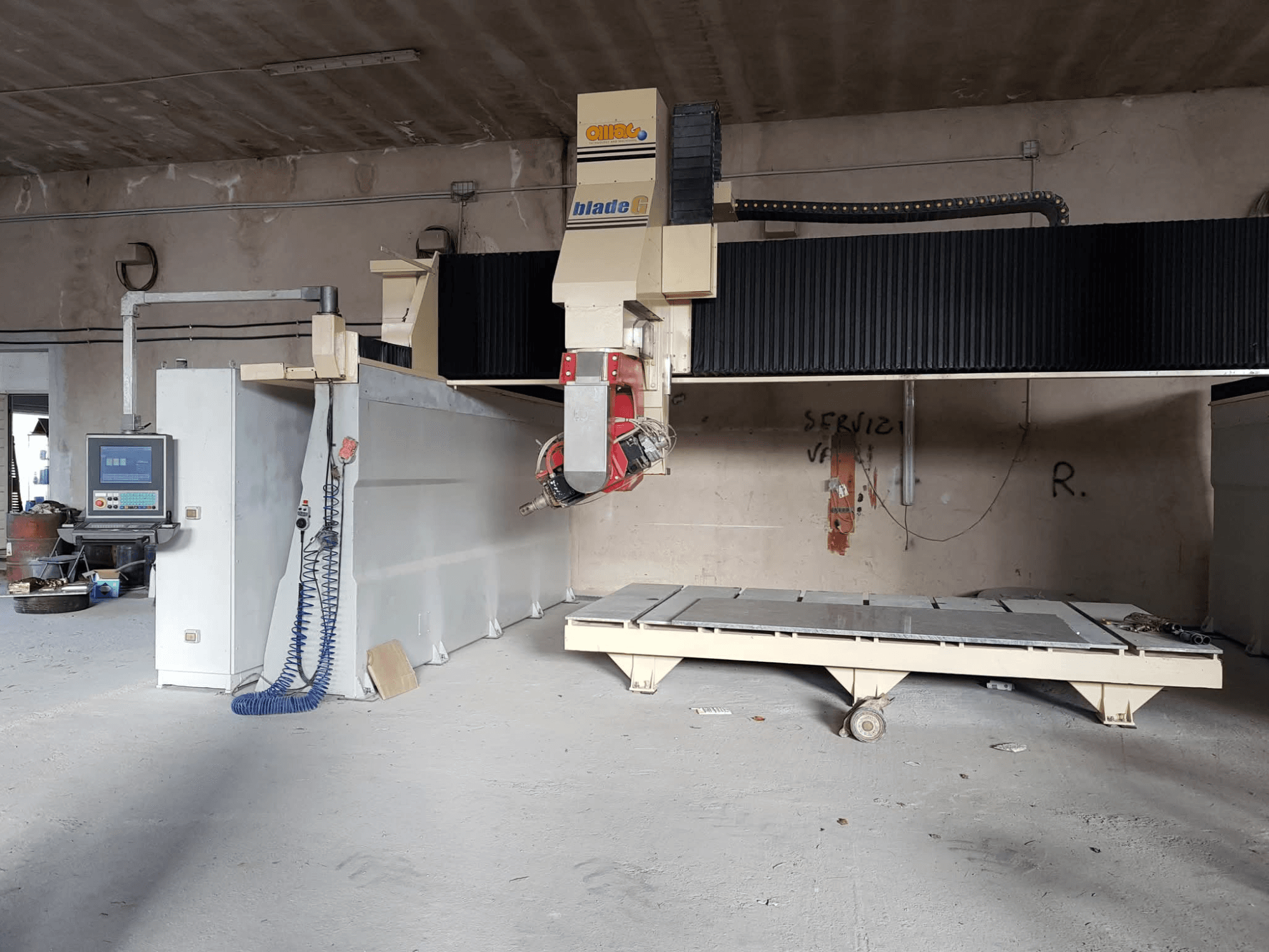 Fraiseuse à portique OMAG Blade G dans un atelier, vue de face avec le panneau de commande et le grand banc de fraisage visibles.