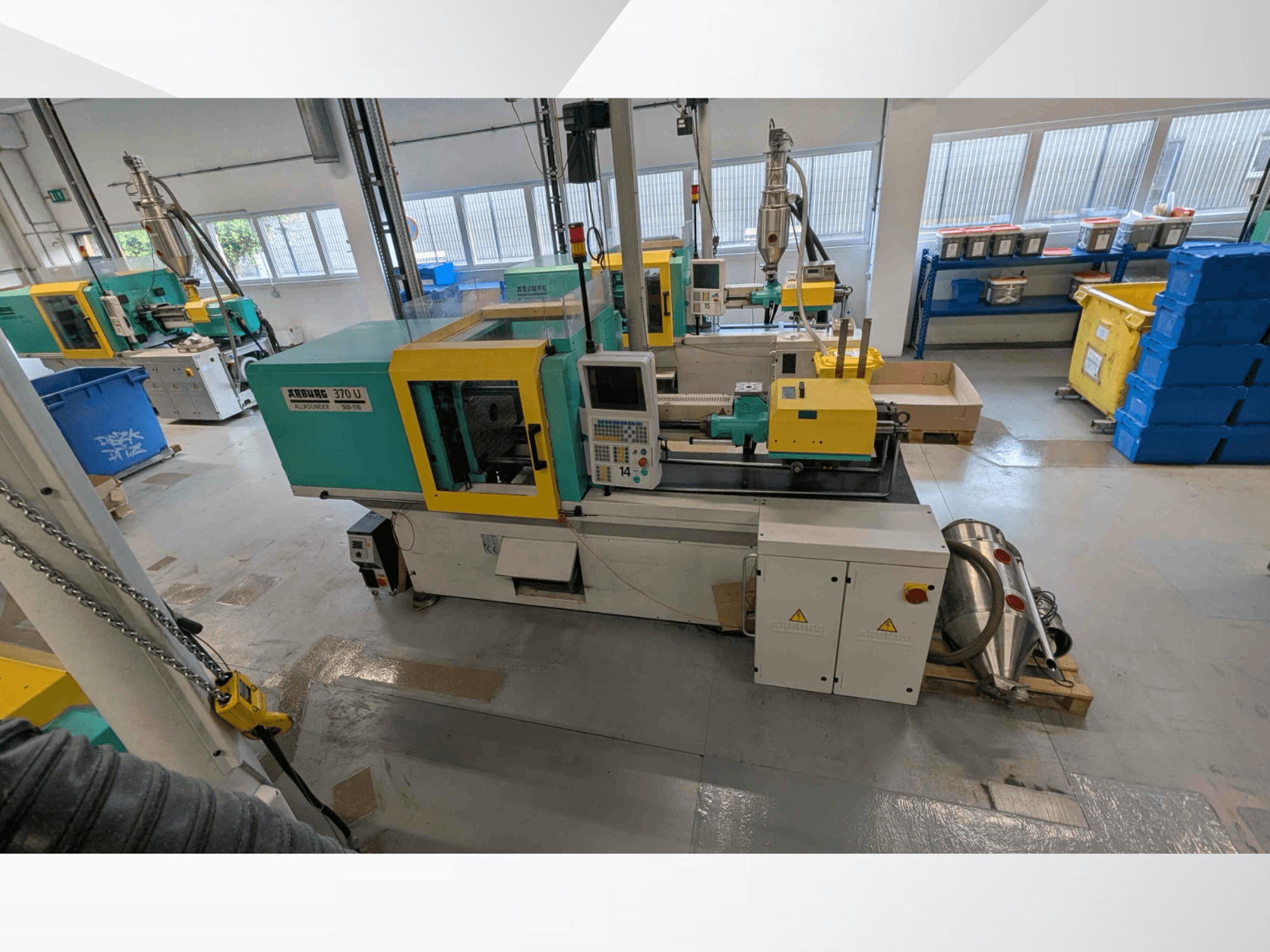 Vue de face d'une presse à injection verticale Arburg 370 U 500-170, avec son panneau de commande et ses composants mécaniques, dans un atelier.