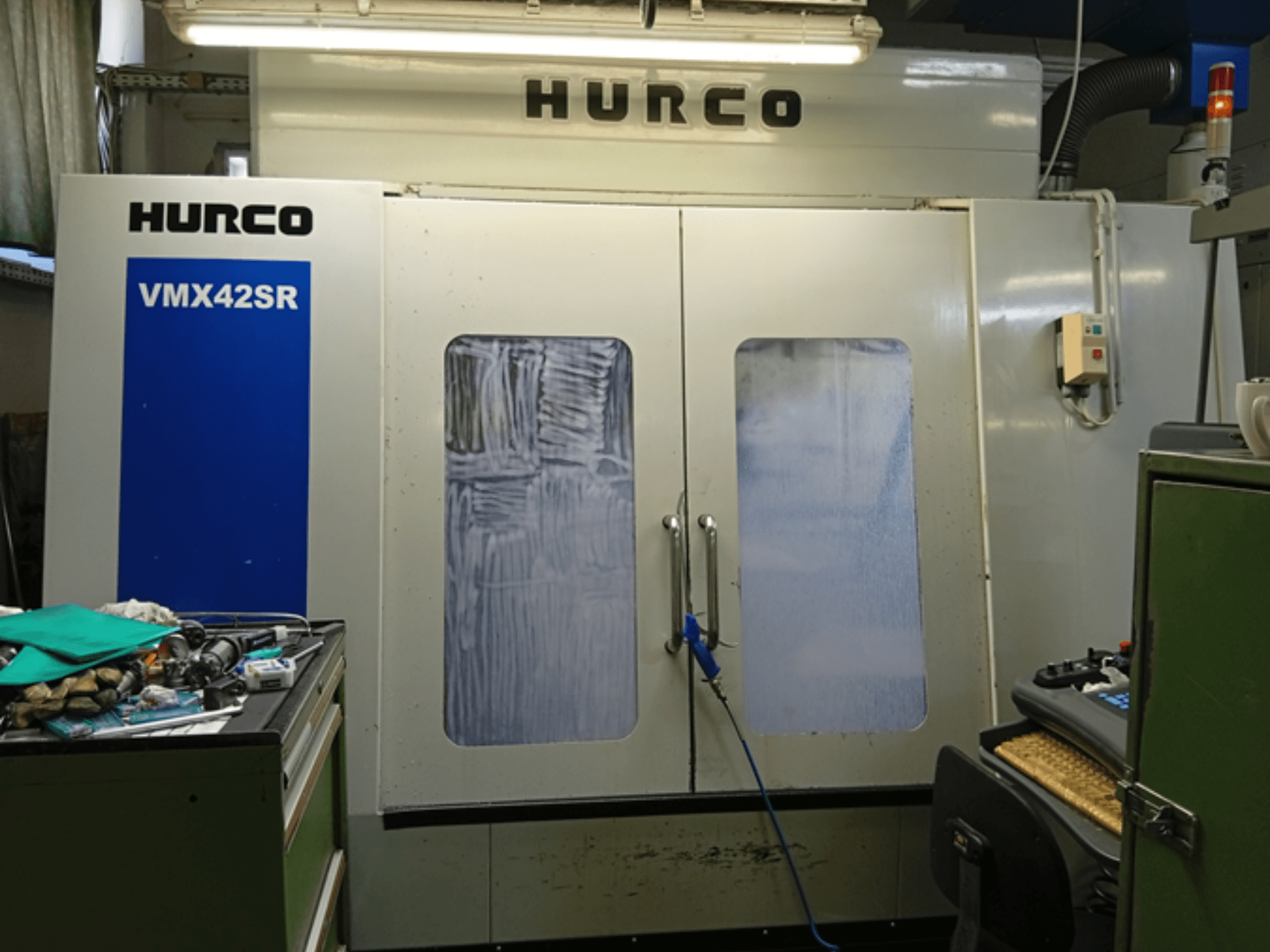 Centre d'usinage vertical Hurco VMX 42SR en vue frontale, avec panneau bleu, interface de commande et espace de travail propre.