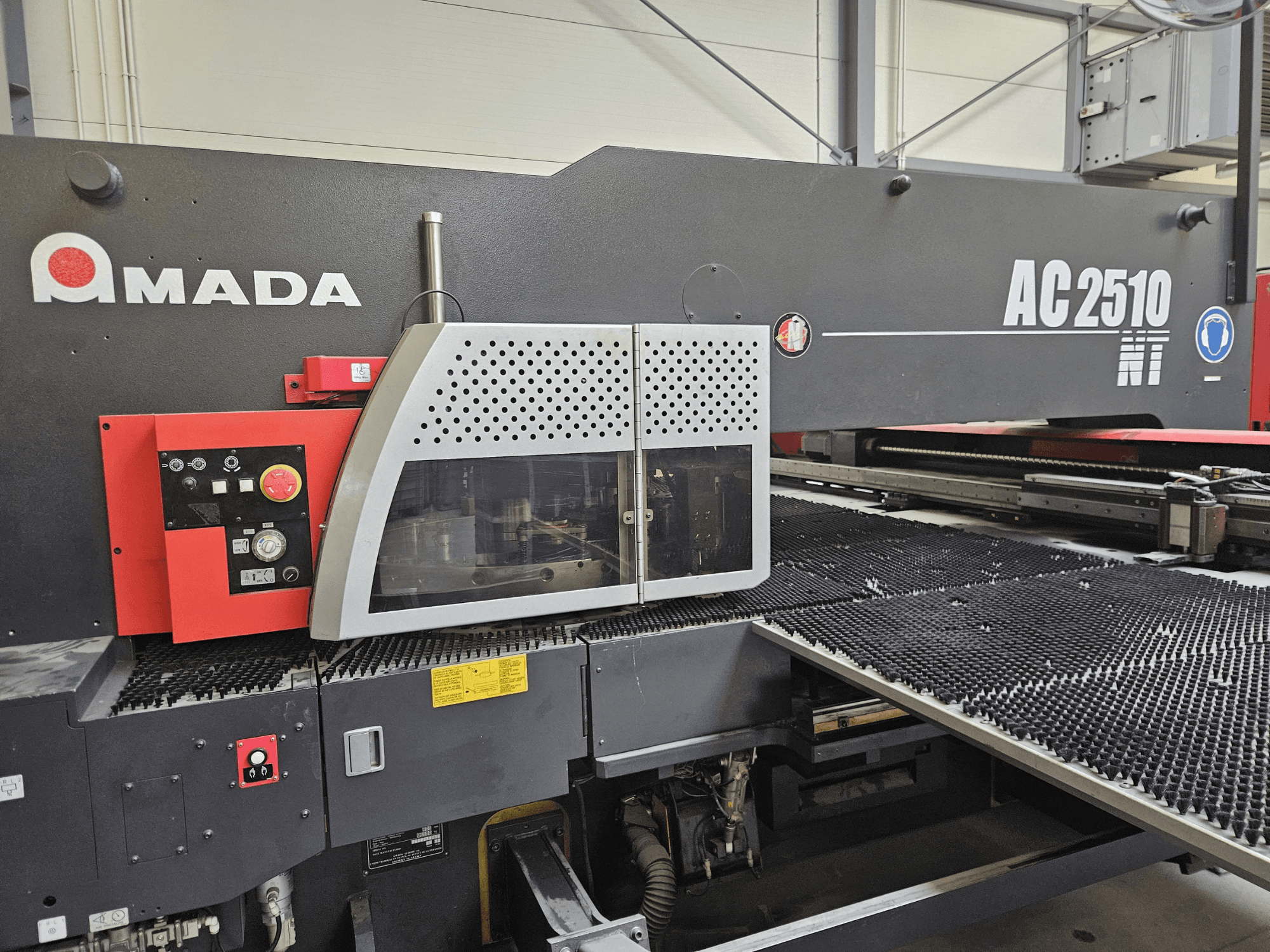 Machine de découpe laser Amada AC2510 NT, vue de face, comportant un panneau de commande avec des boutons, des touches et un couvercle de sécurité.