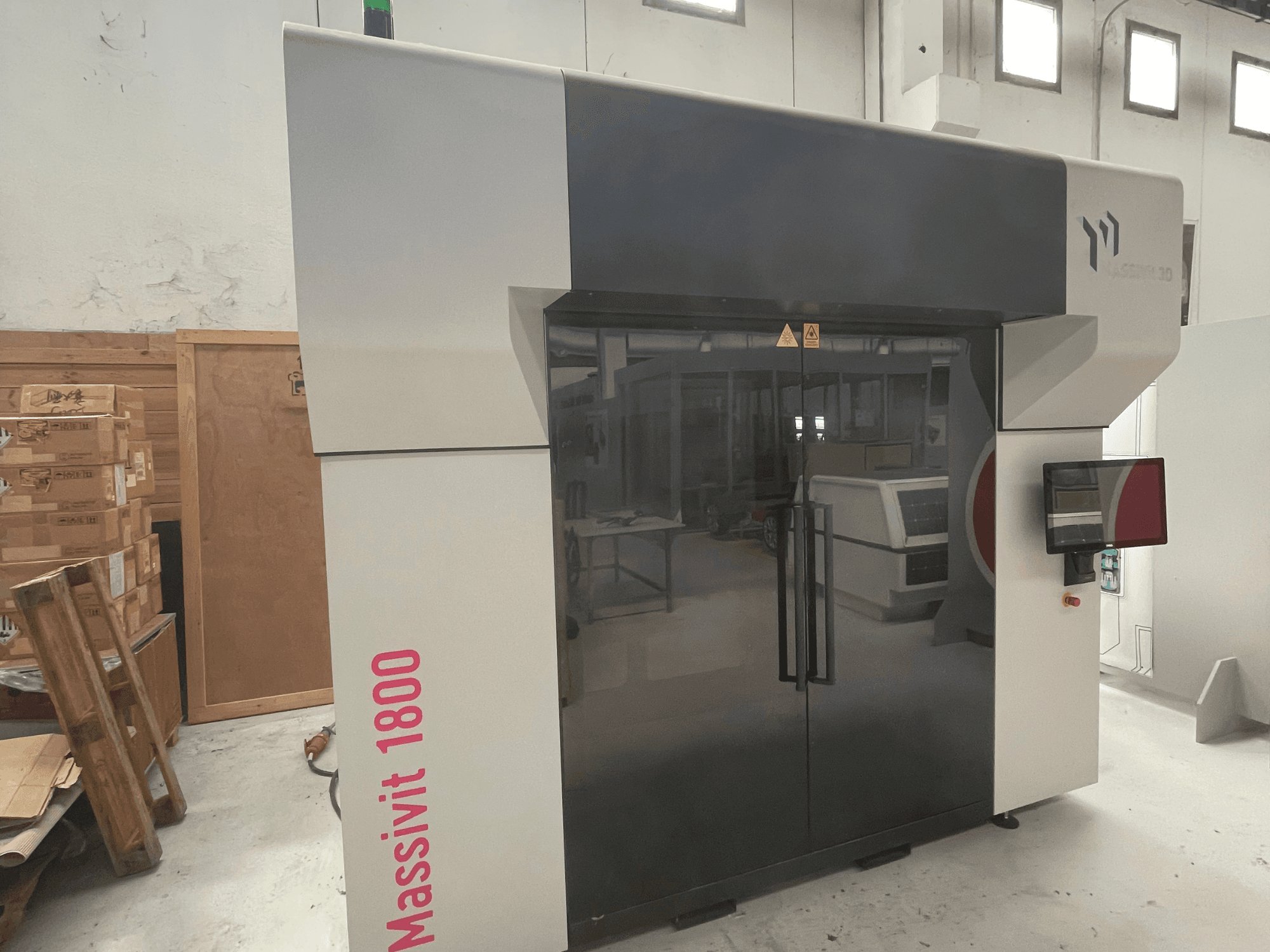 Imprimante 3D à plastique MASSIVIT Massivit 1800 vue de profil, dotée d'un écran tactile et d'un design épuré en noir et blanc.