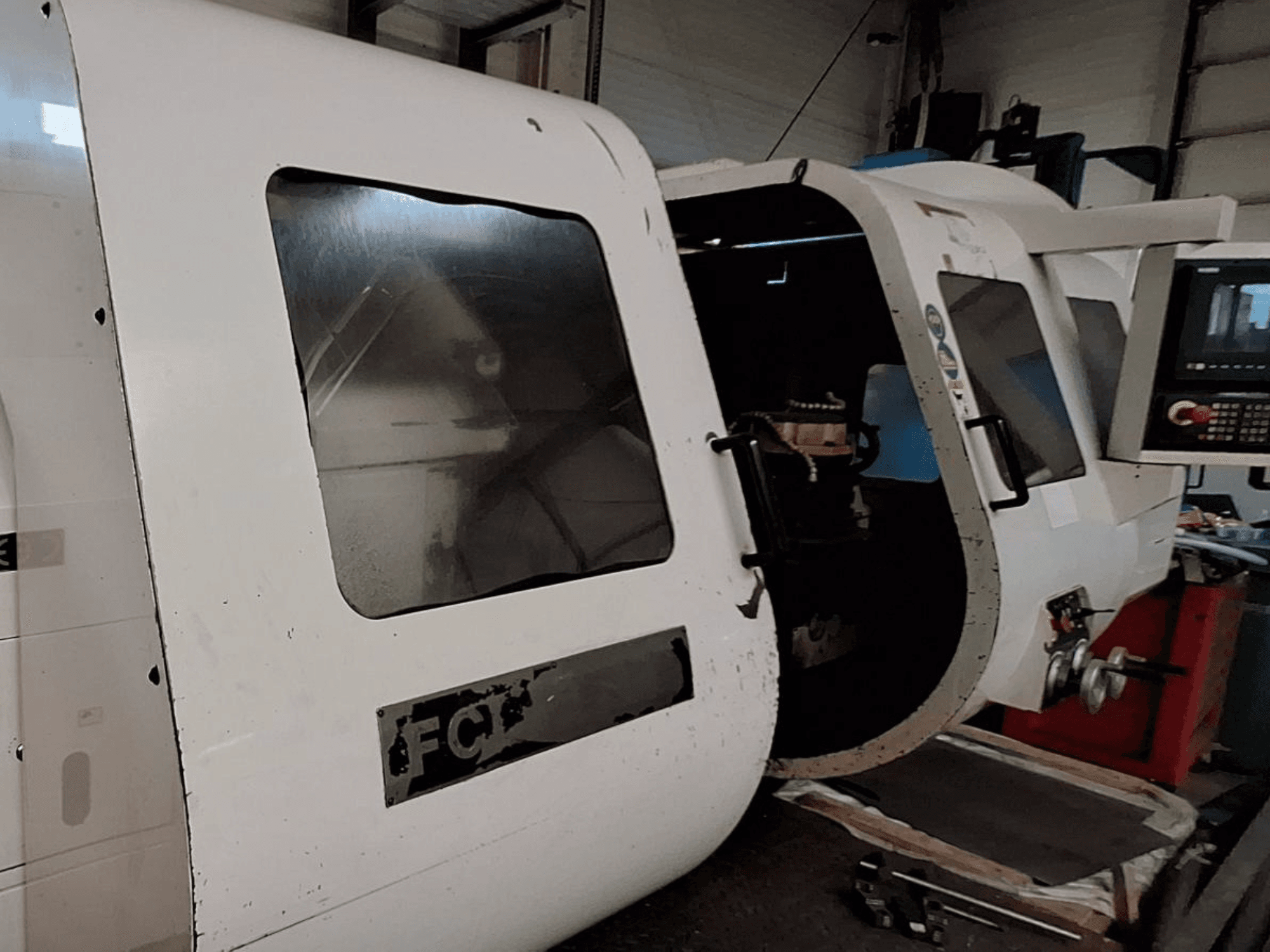 Machine CNC blanche avec panneau de commande visible et porte ouverte, présentant les composants intérieurs ; vue de face. Marque : FCT.
