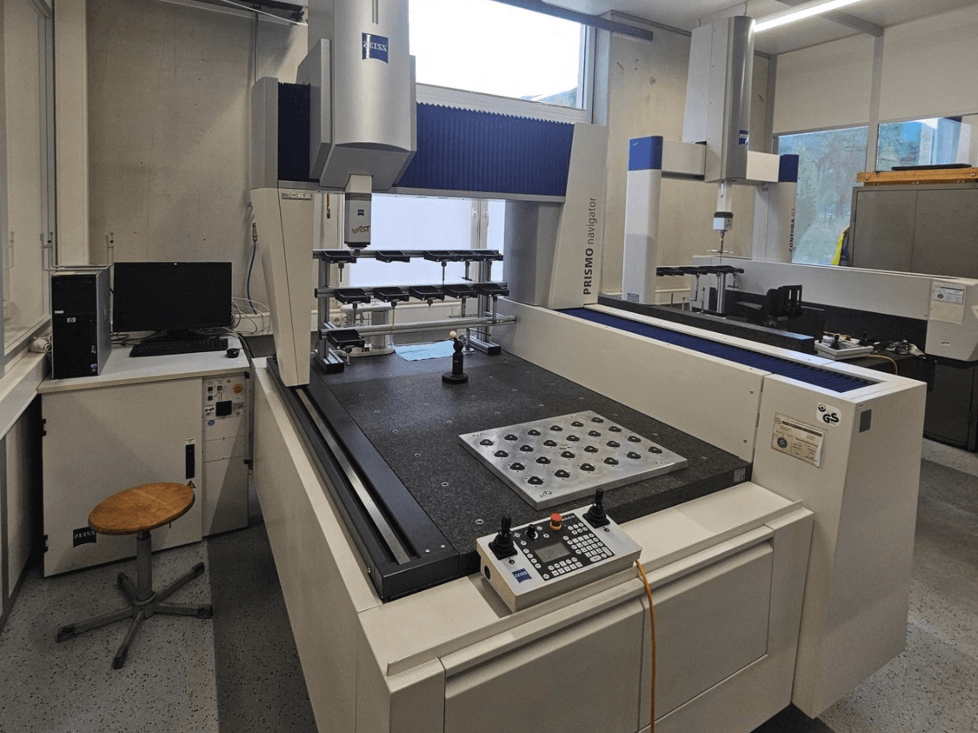 Machine à mesurer tridimensionnelle (MMT) ZEISS Prismo Navigator 7 dans un laboratoire, vue de face montrant le panneau de commande, la table de travail et l'écran.