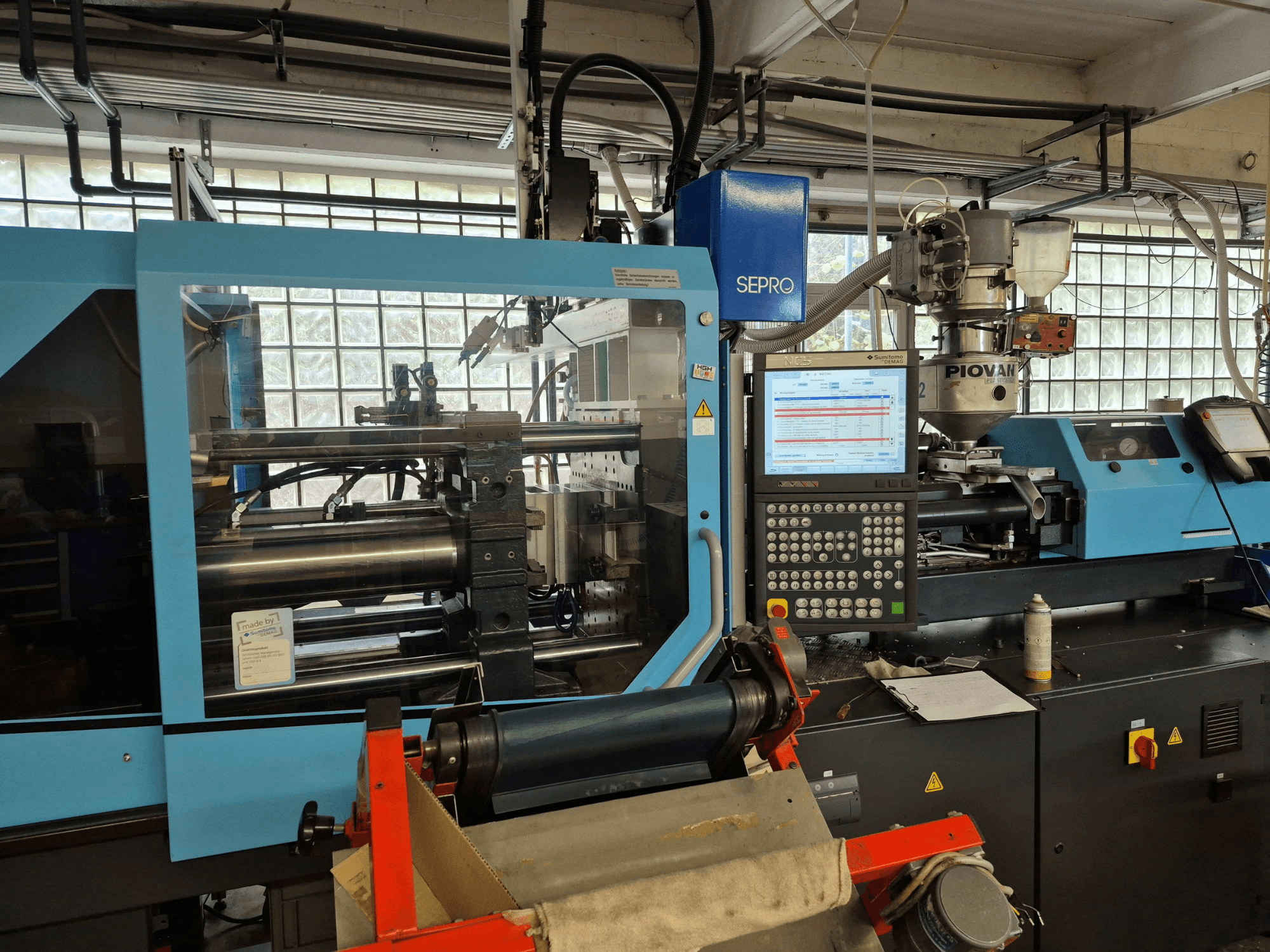 Presse à injection hydraulique SUMITOMO SHI DEMAG Systec 120/470-430, vue de face montrant le panneau de commande et le système d'alimentation.