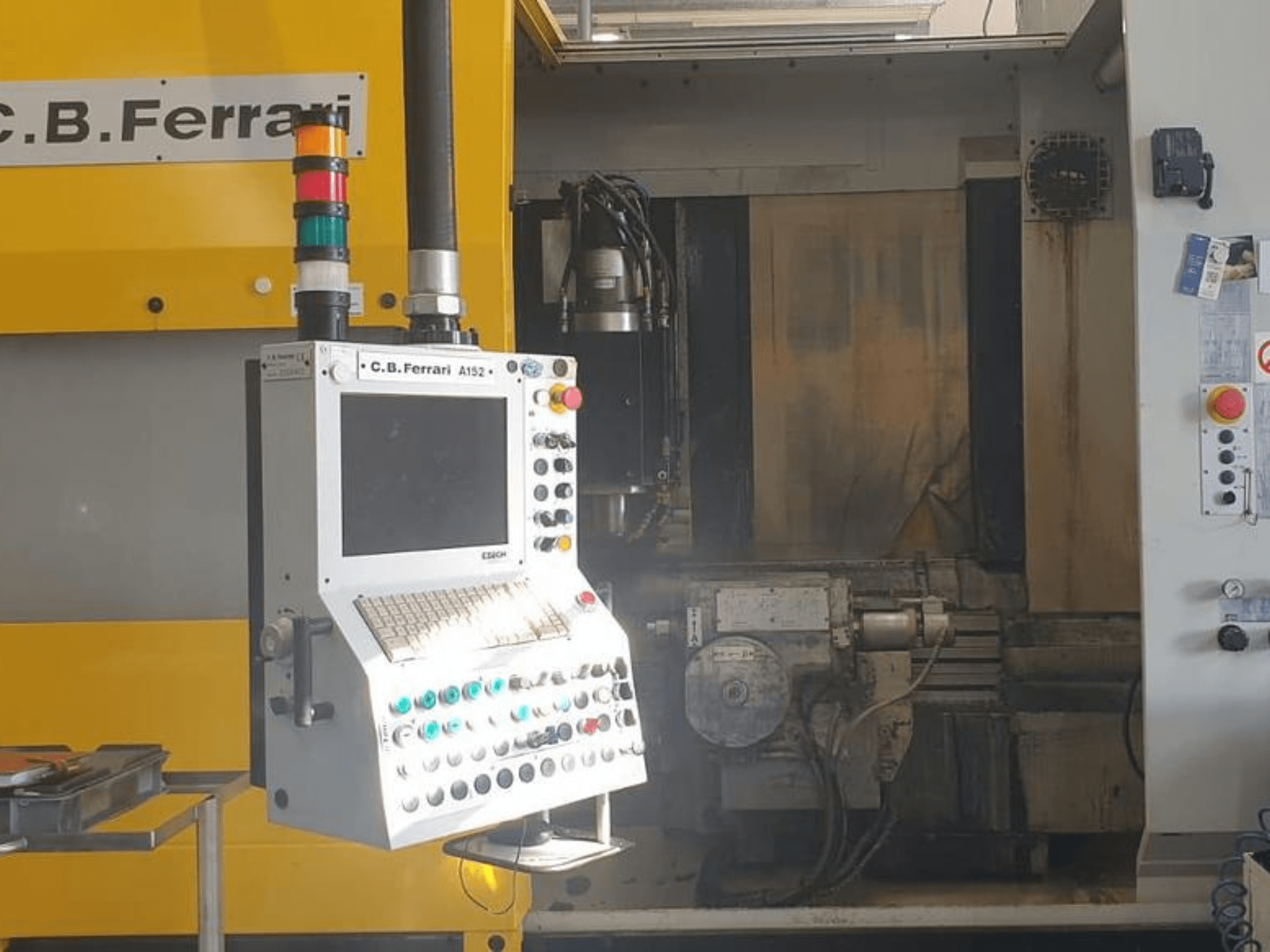Vue avant du centre d'usinage vertical C.B. Ferrari A152, montrant le panneau de commande avec les boutons et les composants du moteur sur la machine.