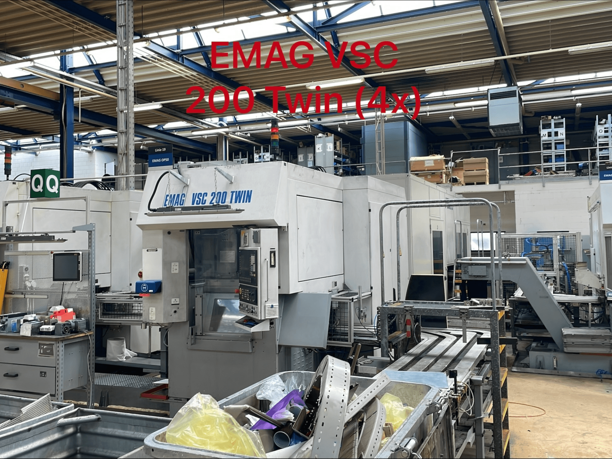 Tour vertical EMAG VSC 200 TWIN dans une usine, vue de face montrant les commandes et la zone de stockage des outils.
