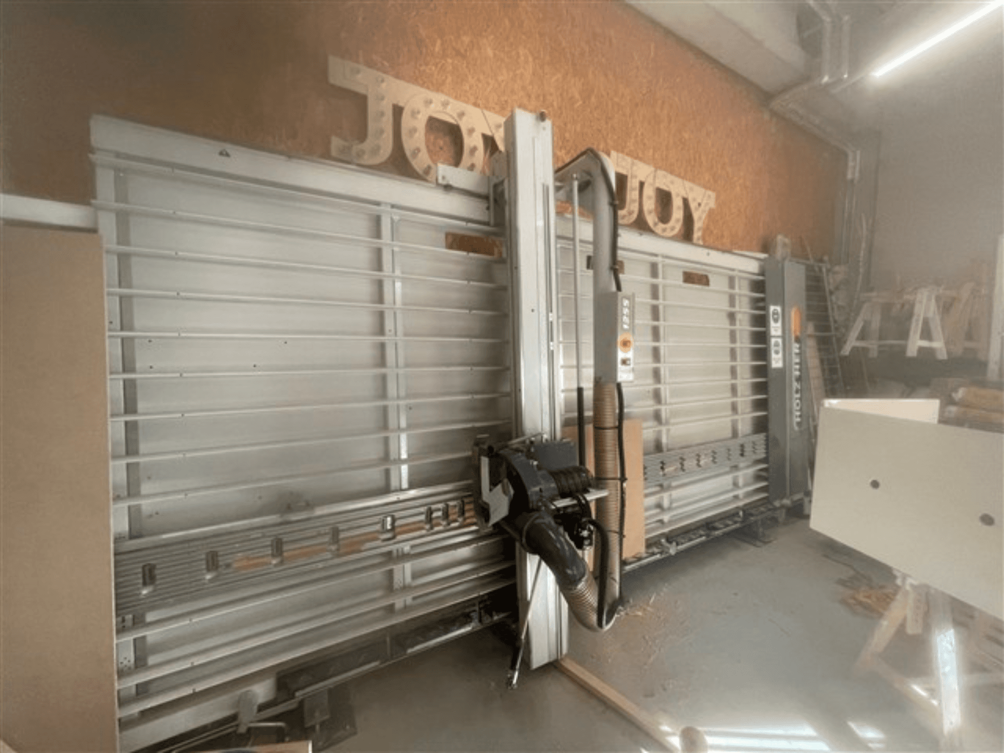 Scie à panneaux horizontale, marque Holz-Her, vue latérale, présentant la lame de scie, l'aspiration des poussières et l'espace de rangement.