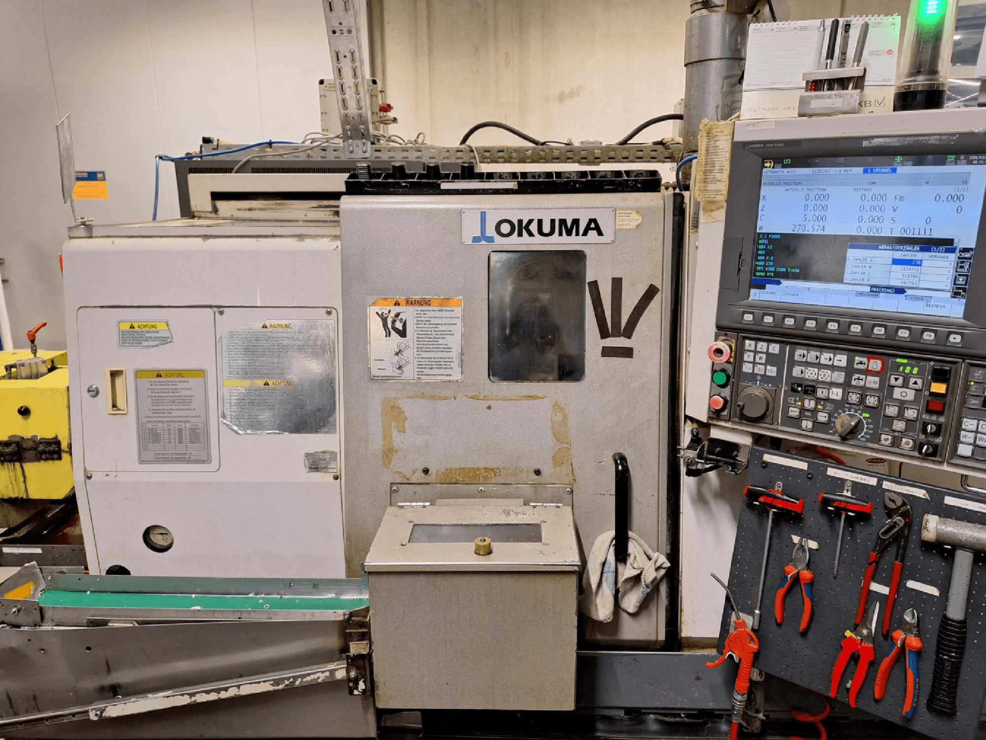 Tour horizontal Okuma LB200-MW, vue de face, avec le panneau de commande et les outils visibles sur le côté.