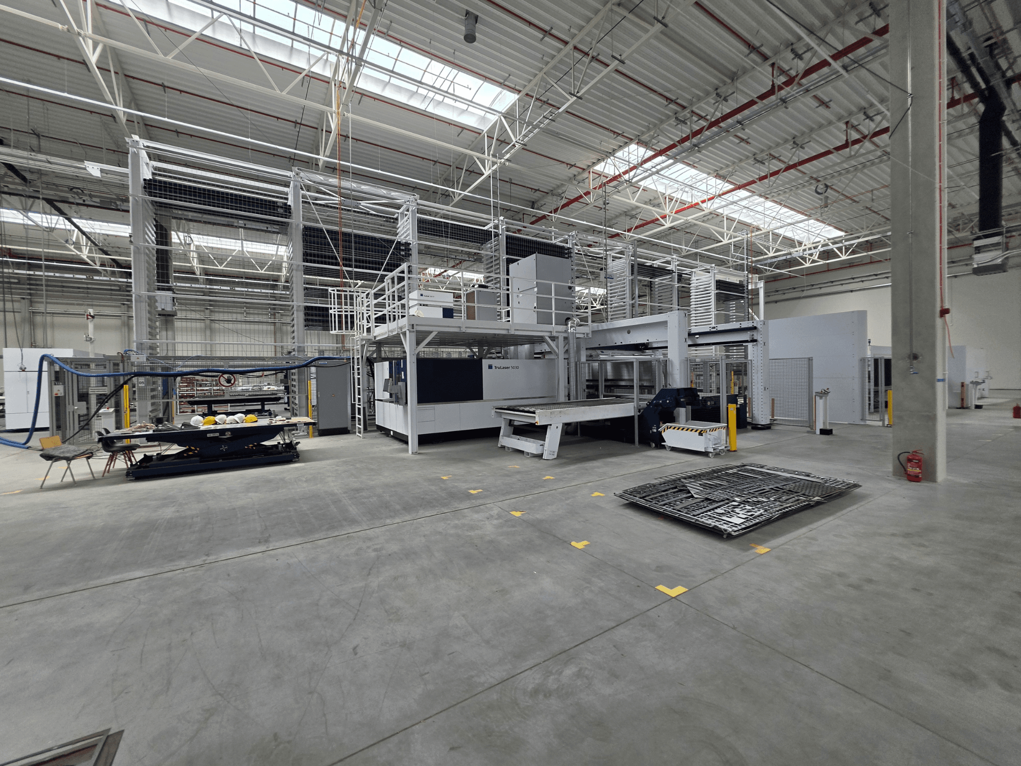Système automatisé de production de tôles TRUMPF : vue de profil montrant les machines, l'espace de travail et les outils dans un grand environnement industriel.