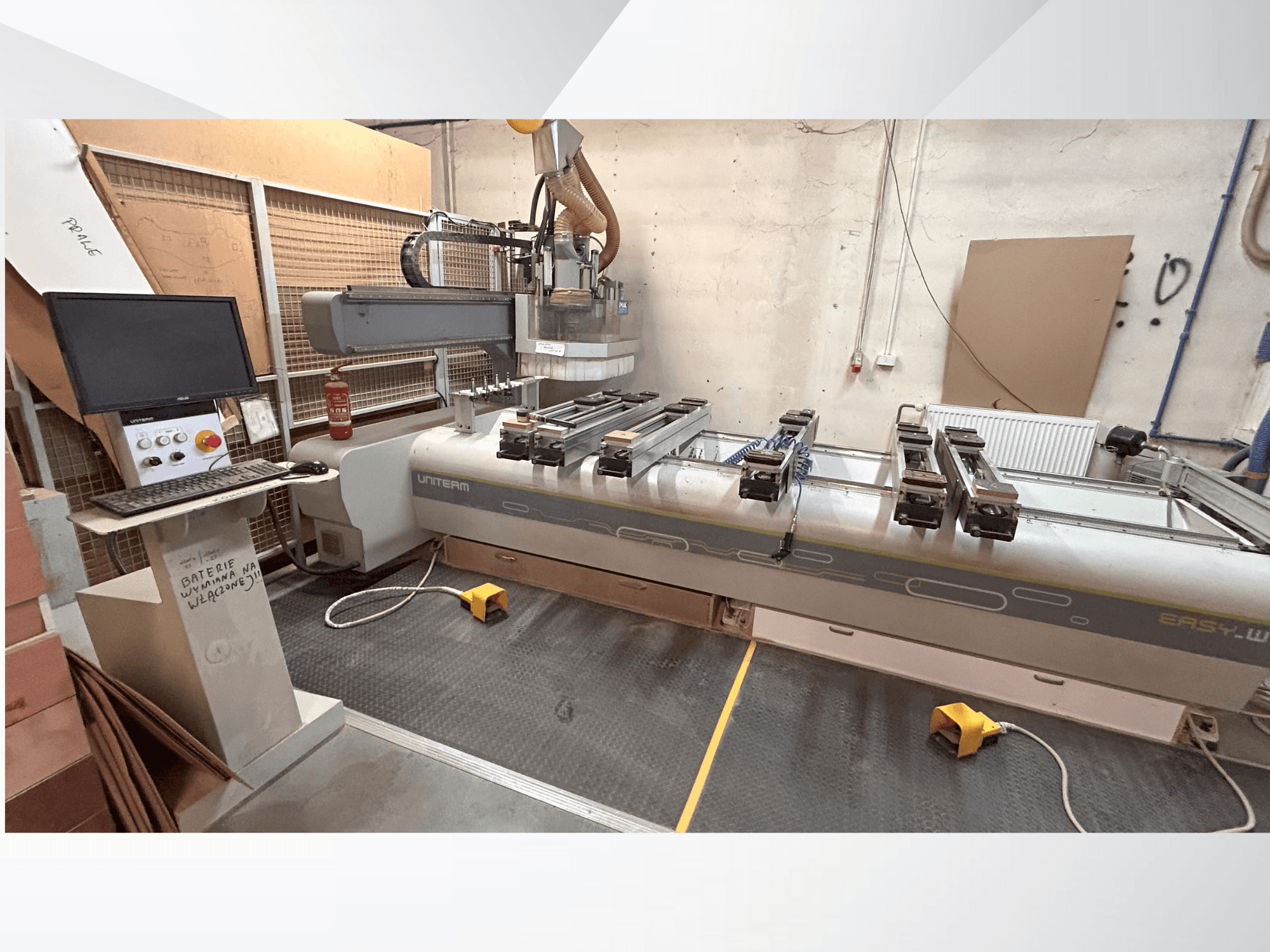 Vue de face d'une machine CNC UNITEM EASY-W, avec un panneau de commande, un moniteur et des pièces serrées sur la table de travail.