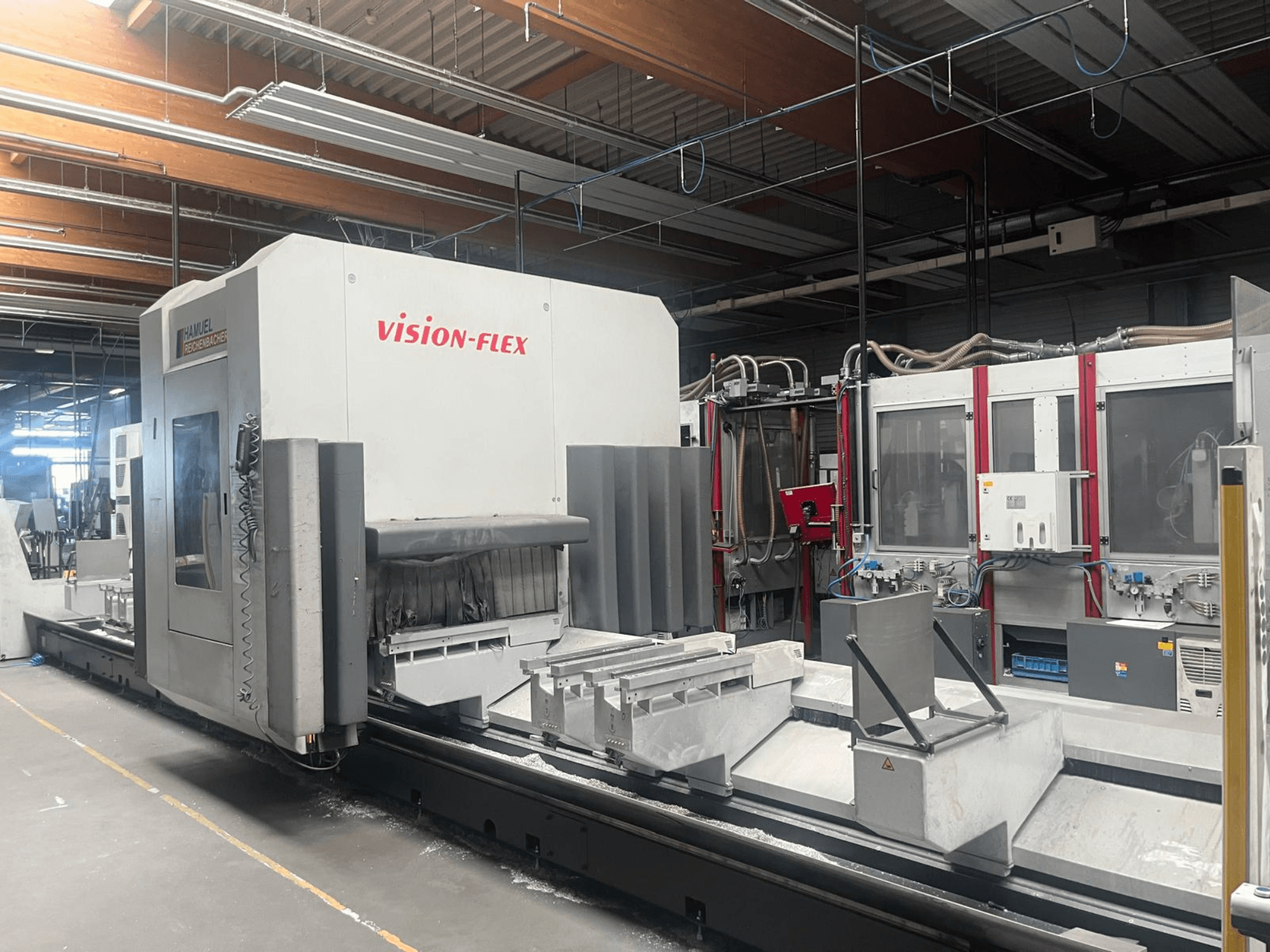 Centre d'usinage vertical Hamuel Reichenbacher Vision Flex, vue de profil montrant la zone de travail et les commandes dans un environnement industriel.