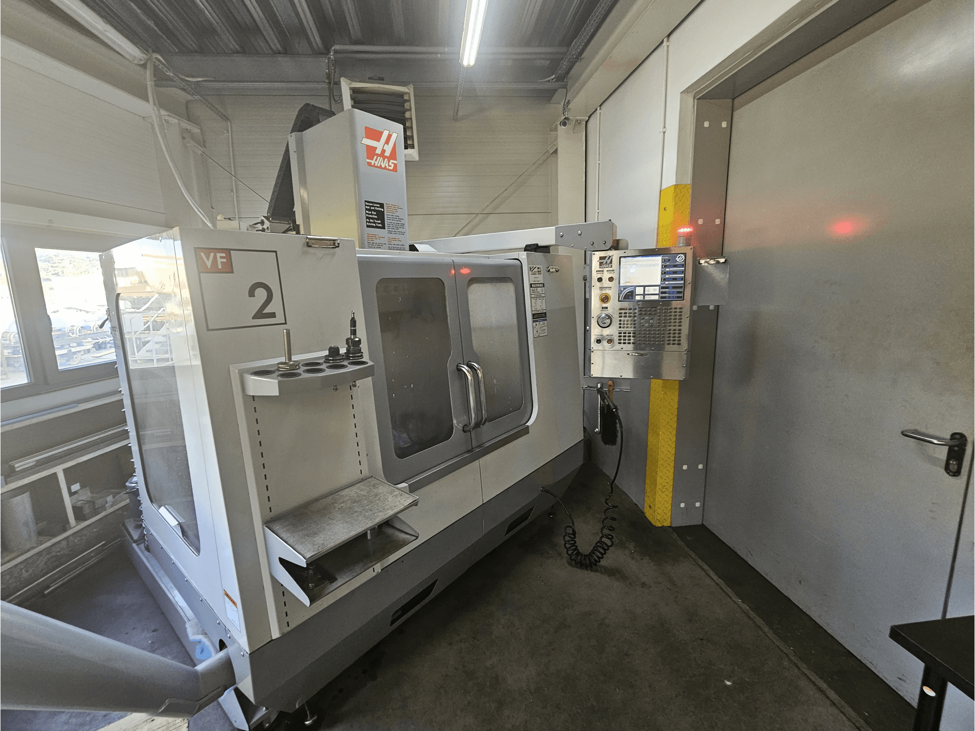 Fraiseuse CNC Haas VF-2, vue de face, montrant le panneau de commande, les porte-outils et une fenêtre claire sur l'espace de travail.