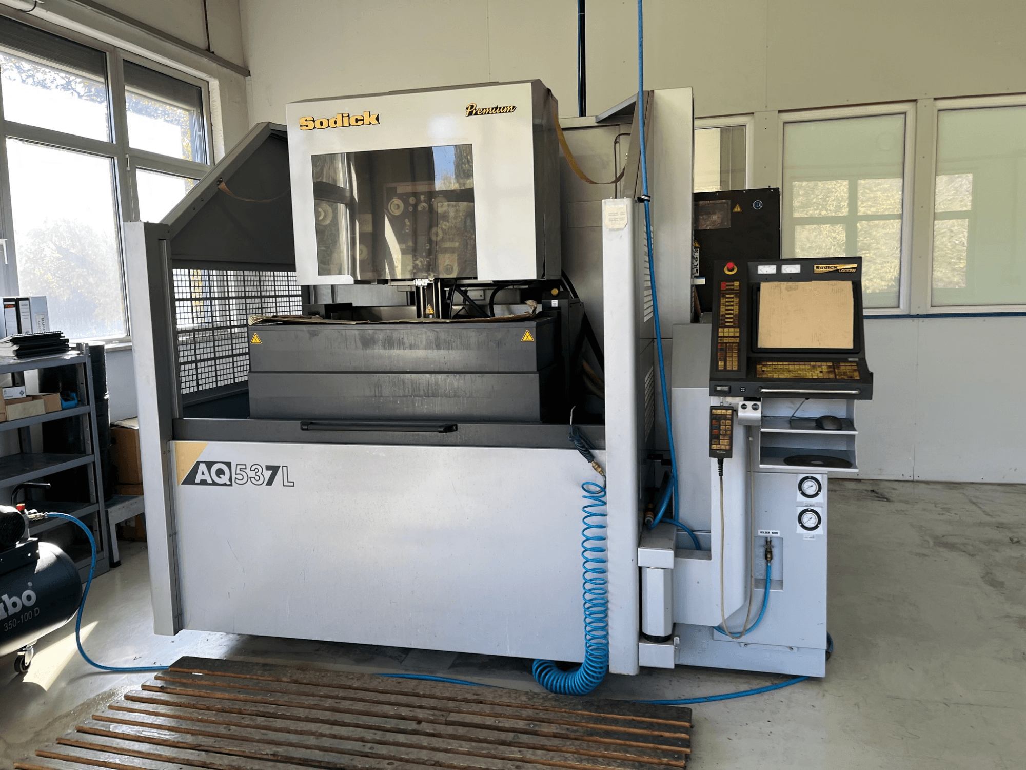 Machine à électroérosion (EDM) Sodick AQ537L vue de face, avec le panneau de commande, les lignes de refroidissement de l'eau et l'espace de travail.