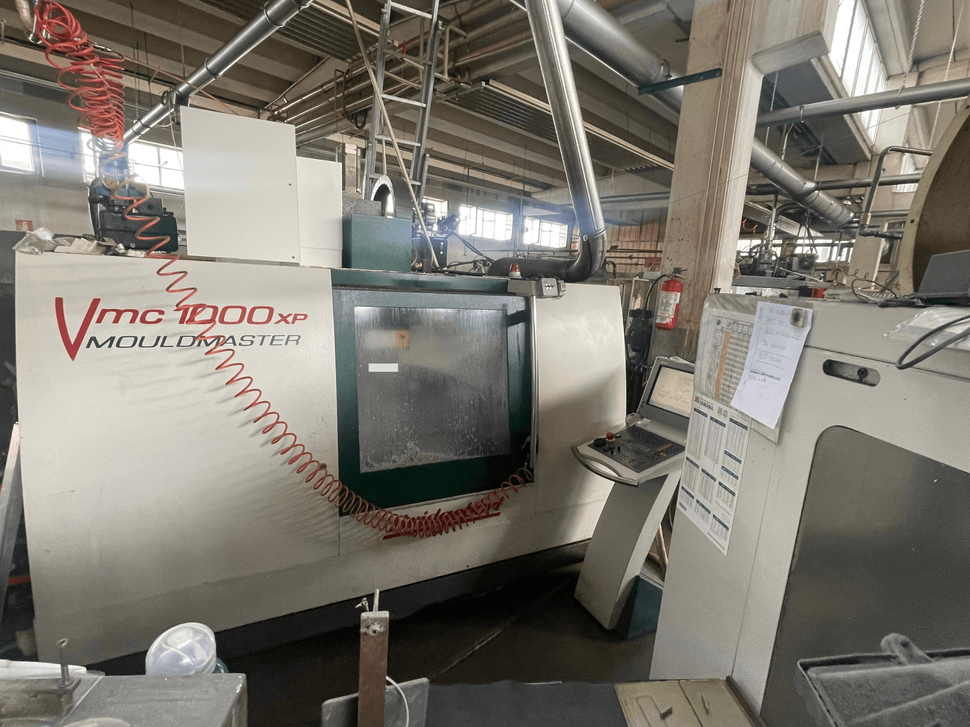 Centre d'usinage vertical Bridgeport VMC 1000, vue de face, montrant le panneau de commande et les détails de la machine dans un environnement industriel.