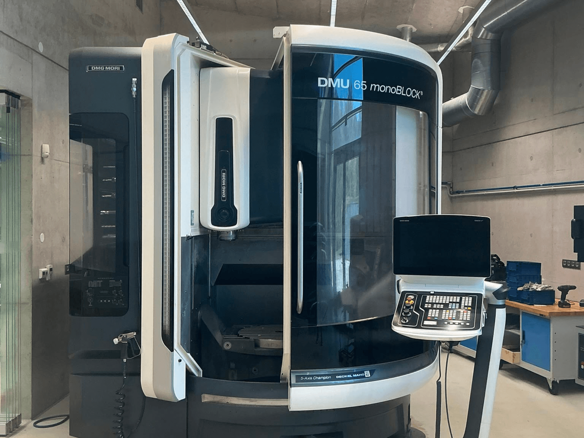 Centre d'usinage vertical DMG MORI DMU 65 monoBLOCK, vue de face, montrant le panneau de commande et les détails de la machine dans un atelier.