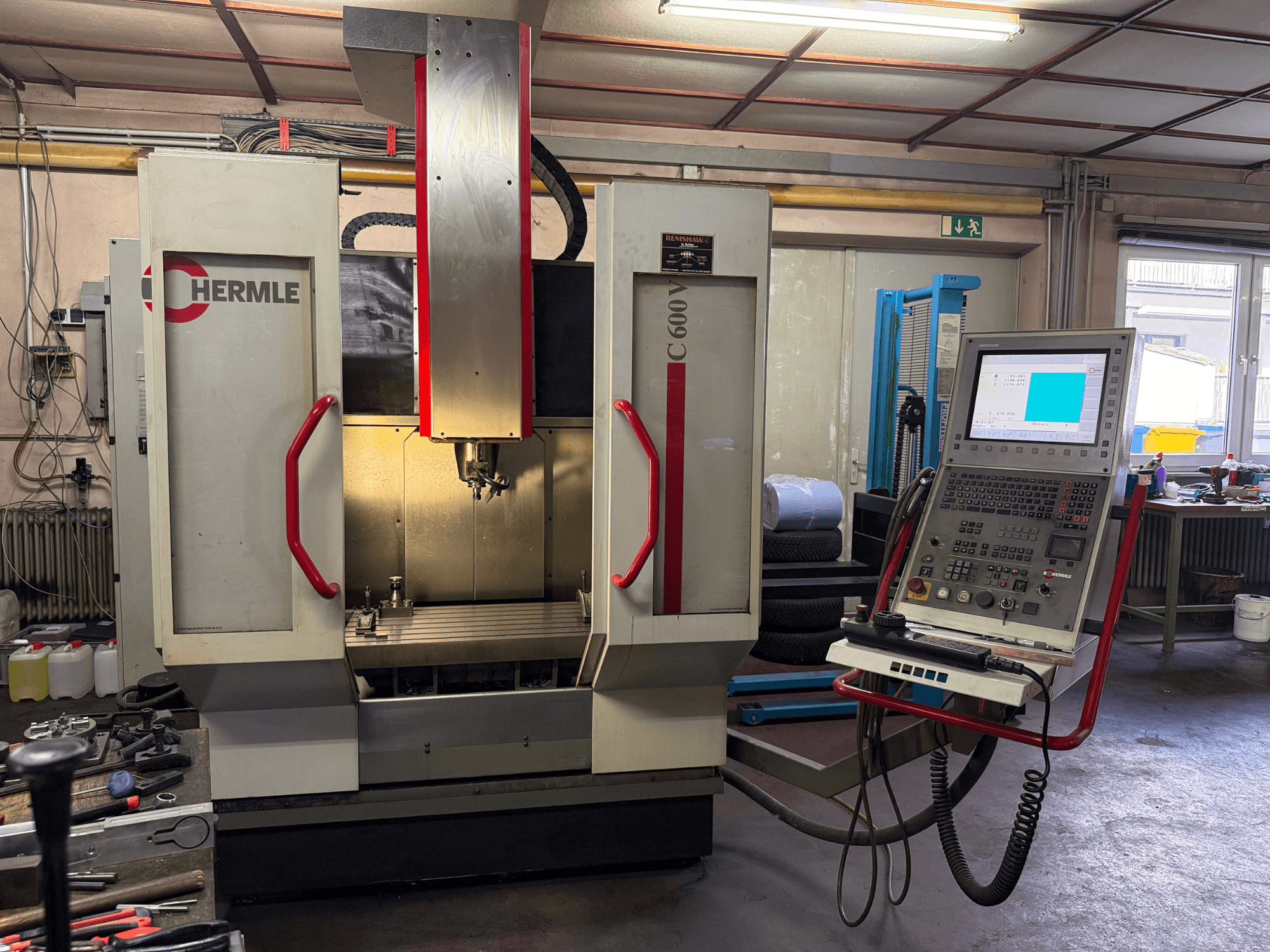 Fraiseuse CNC Hermle C 600 vue de face, dotée d'un panneau de commande avec de nombreux boutons et d'un espace de travail spacieux.