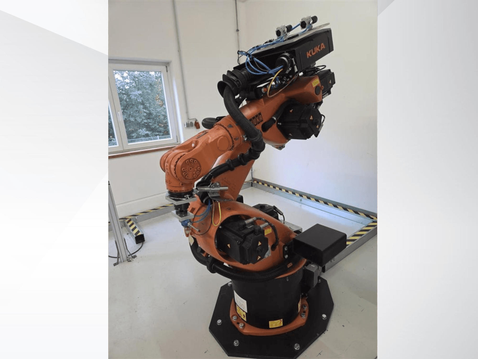 Vue de profil du bras robotisé KUKA KR60 HA, mettant en évidence ses articulations mécaniques et son câblage sur un socle industriel.