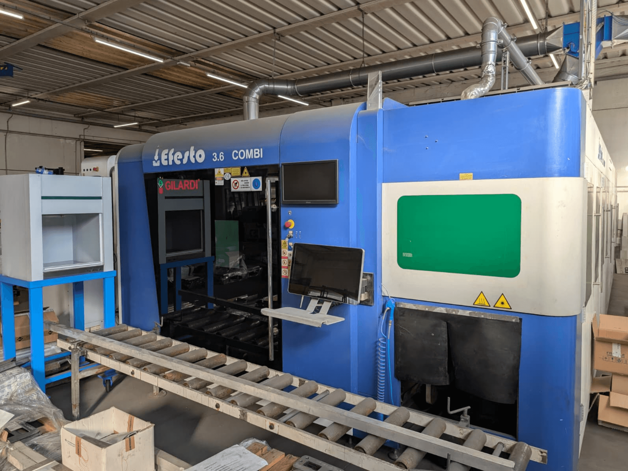 Machine de découpe au laser à fibre EFESTO 3.6 COMBI, vue de profil, avec panneau de commande et voyants de sécurité, dans un boîtier bleu.