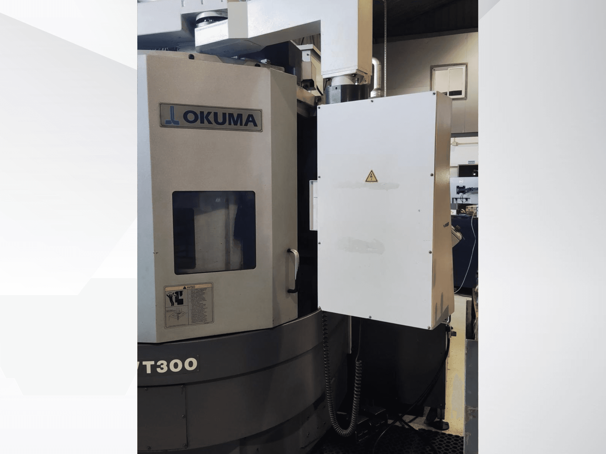 Tour vertical LVT300 d'Okuma, vue de face, présentant le panneau de commande et les dispositifs de sécurité étiquetés.