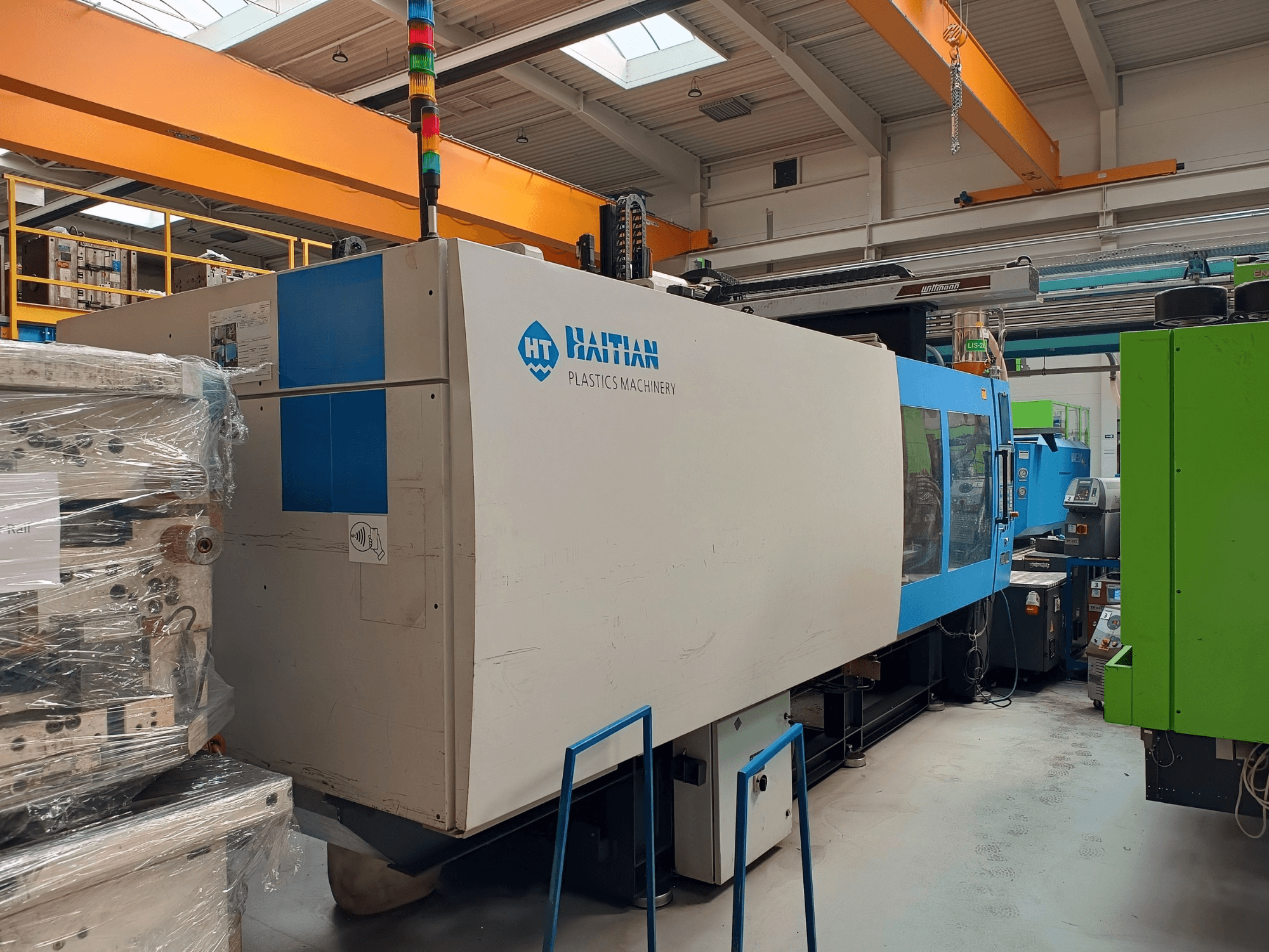 Machine de moulage par injection hydraulique HAITIAN MARS 5300/4500, vue de côté, avec un design bleu et blanc, des zones opérationnelles et un panneau de commande.