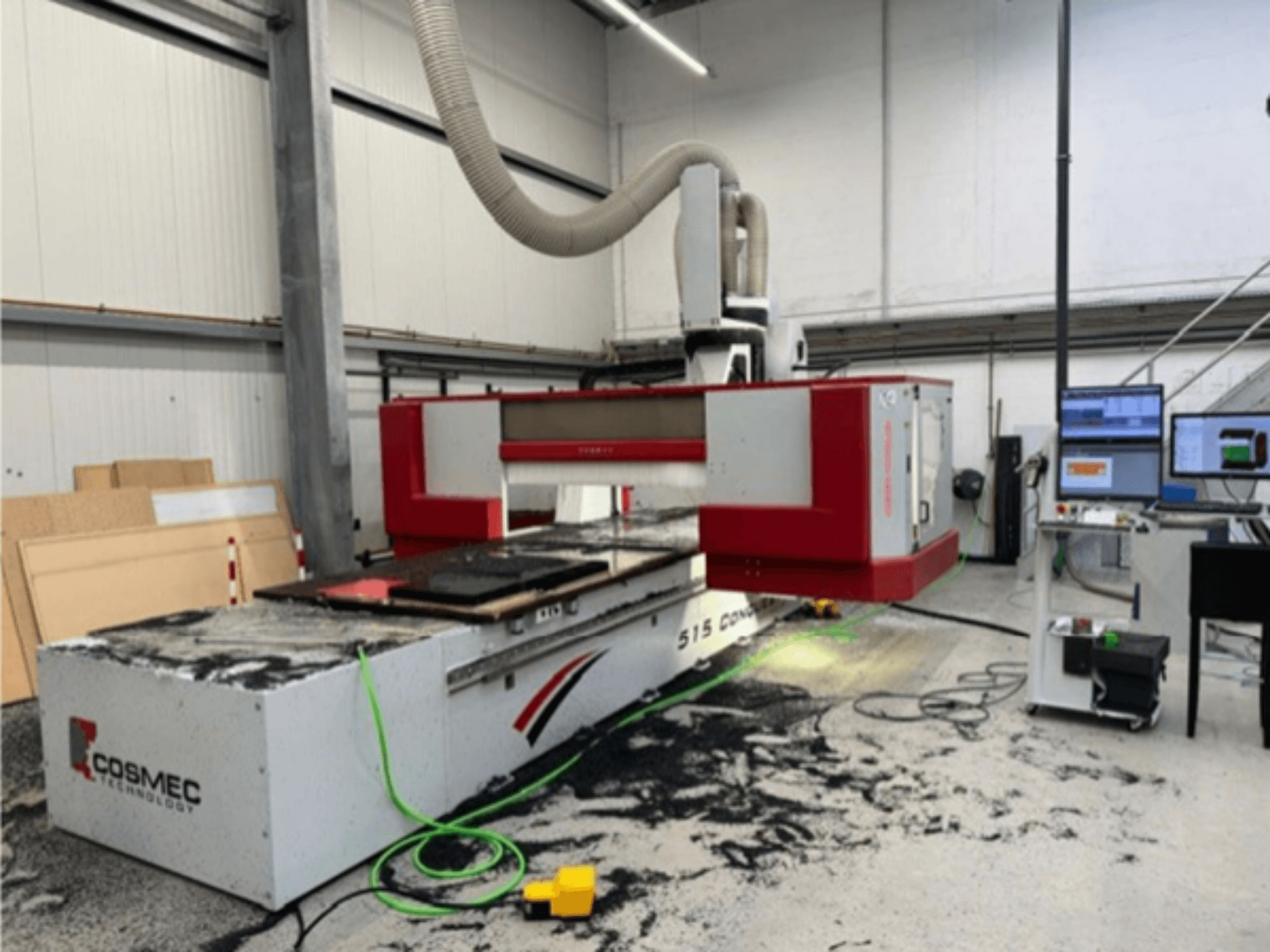 Machine CNC Cosmec 515 dans un atelier avec un terminal d'ordinateur, montrant une vue de face et de la poussière dispersée sur la surface.