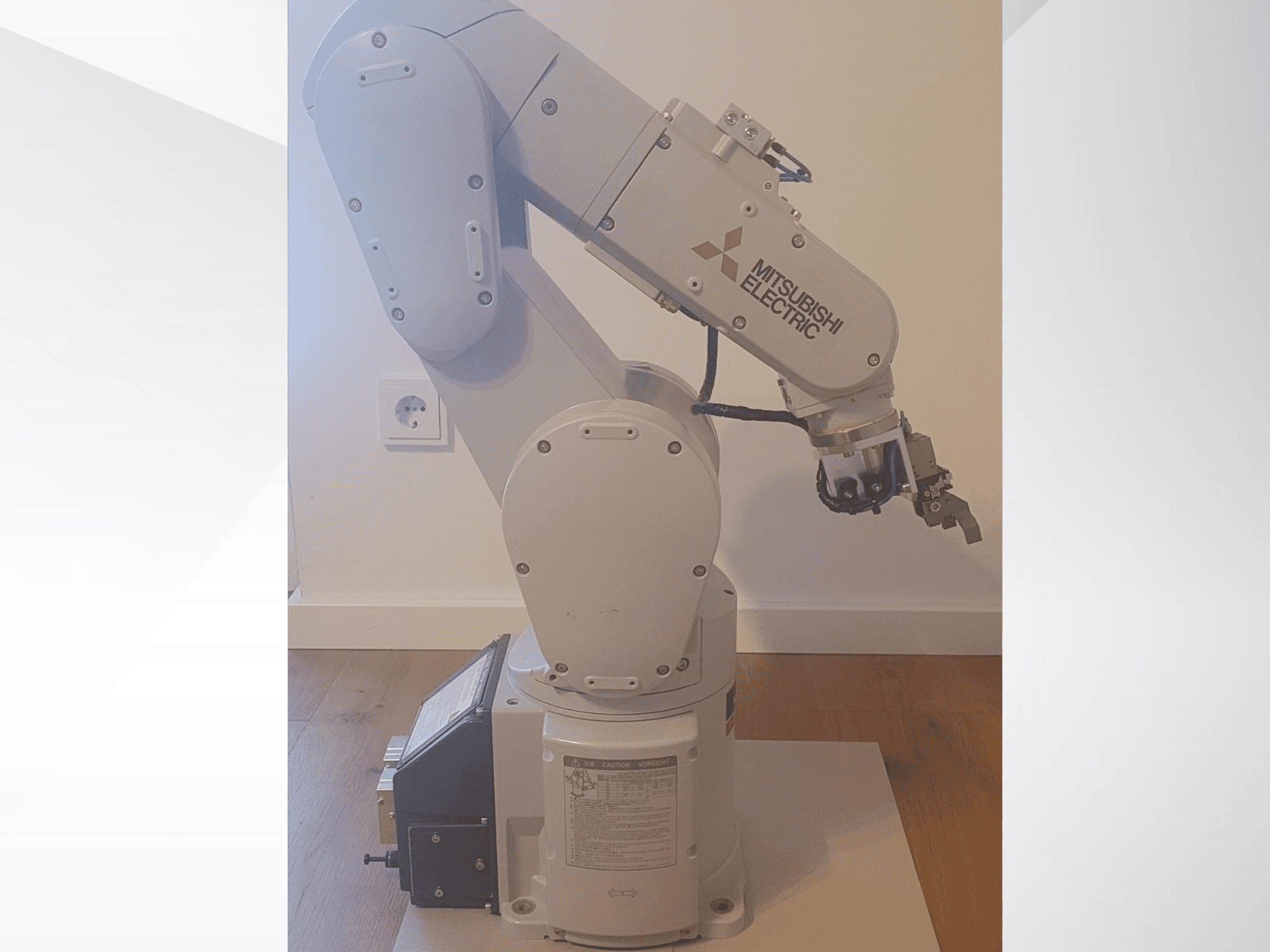 Bras robotique de Mitsubishi Electric, vue latérale, comprenant une pince et un panneau de commande détaillé sur la base pour les réglages de fonctionnement.