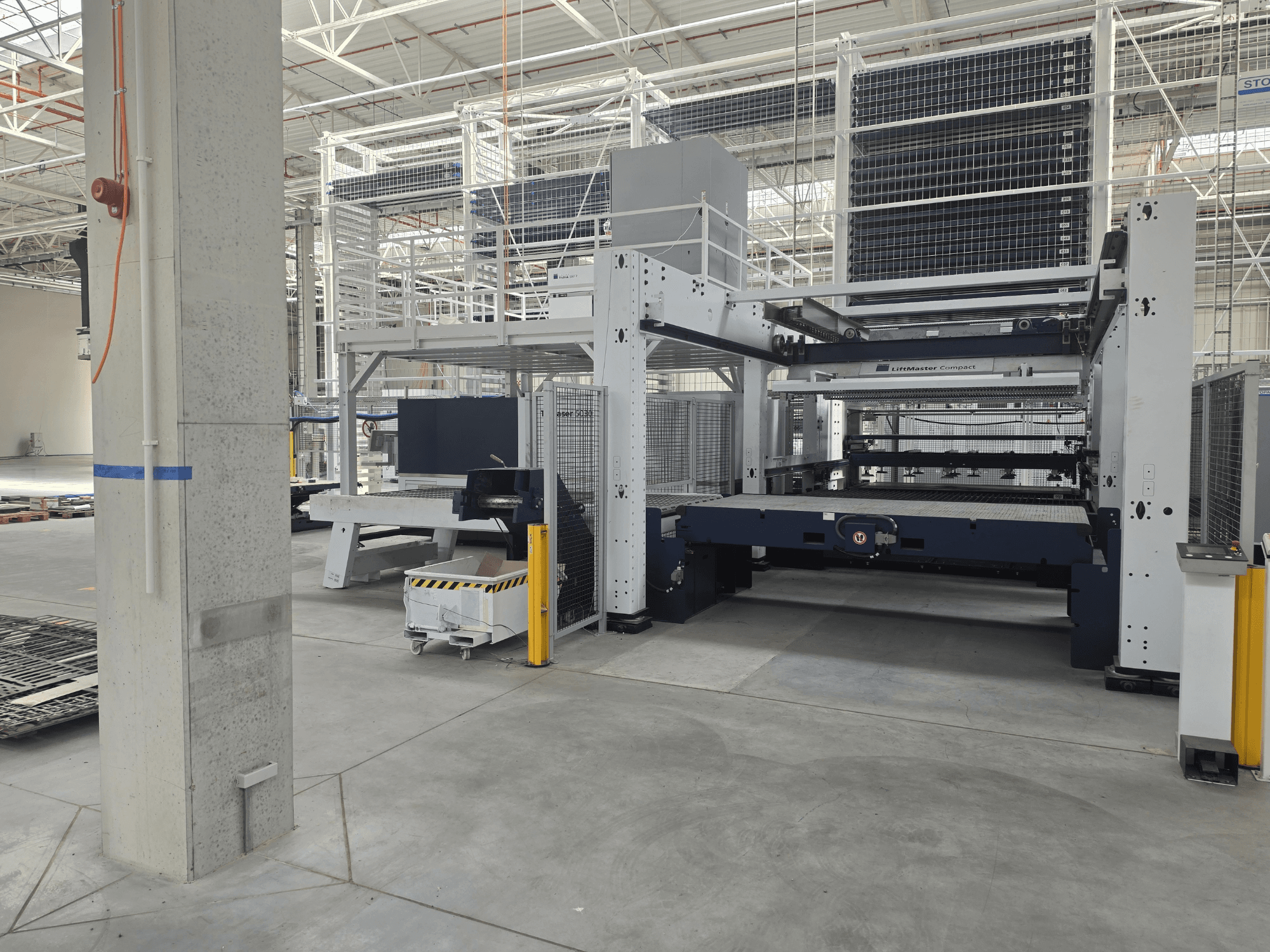 Vue de face de la TRUMPF TruLaser 5030 fiber L76 FMC, présentant la machine de découpe laser à fibre optique dans un vaste environnement industriel.