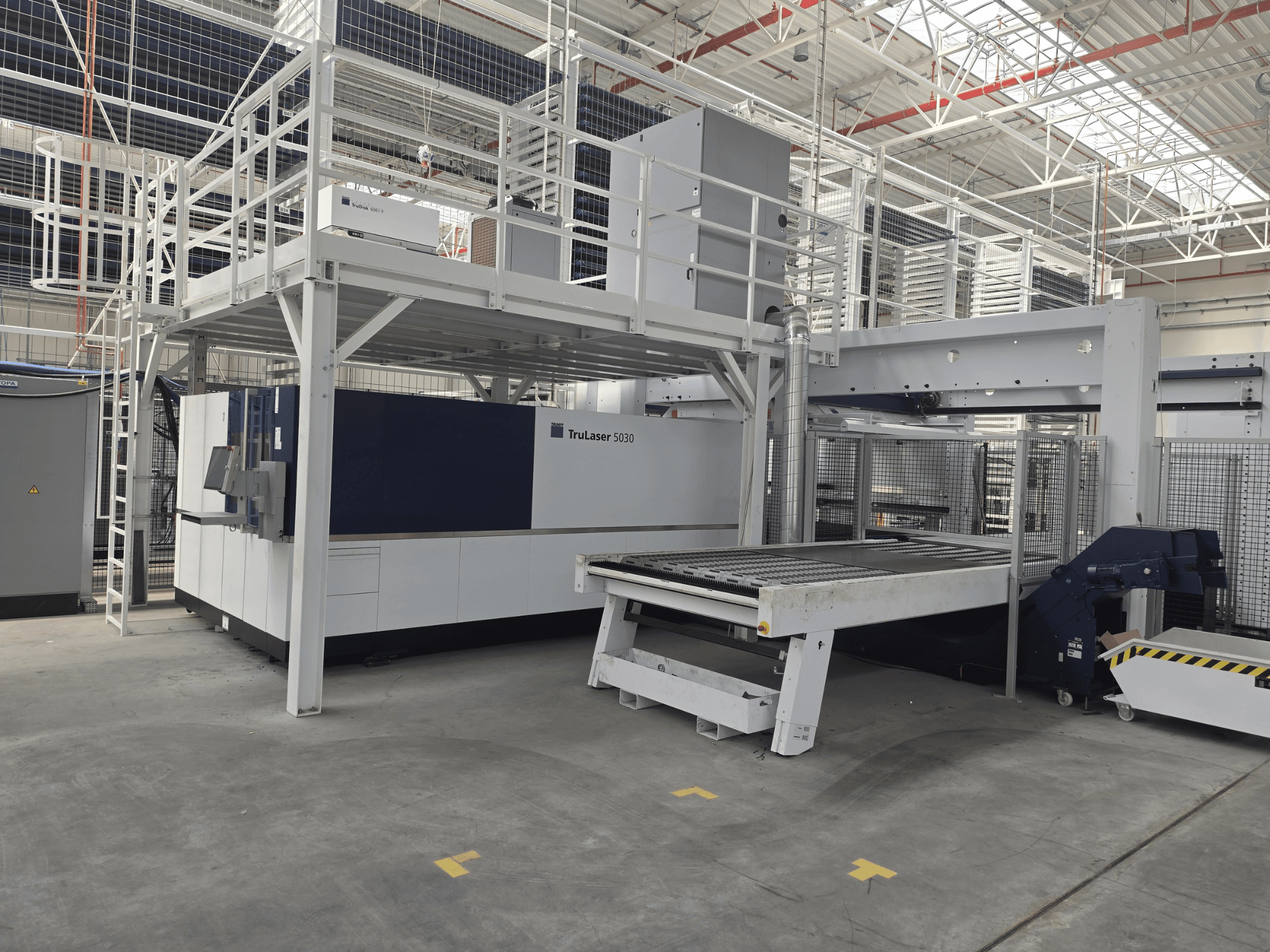 Machine TRUMPF TruLaser 5030 fiber L76 FMC dans un atelier, vue de face montrant la zone de découpe et le mécanisme de chargement/déchargement.