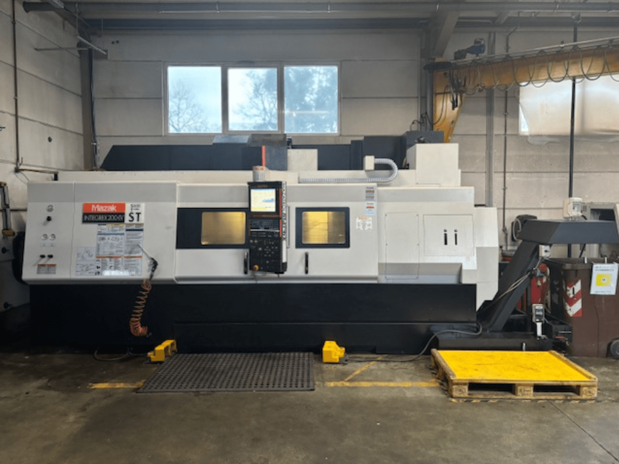 Mazak Integrex 200 SY ST, vue latérale, montrant le panneau de commande, les affichages de fonctionnement et les conduites de liquide de refroidissement dans un atelier.