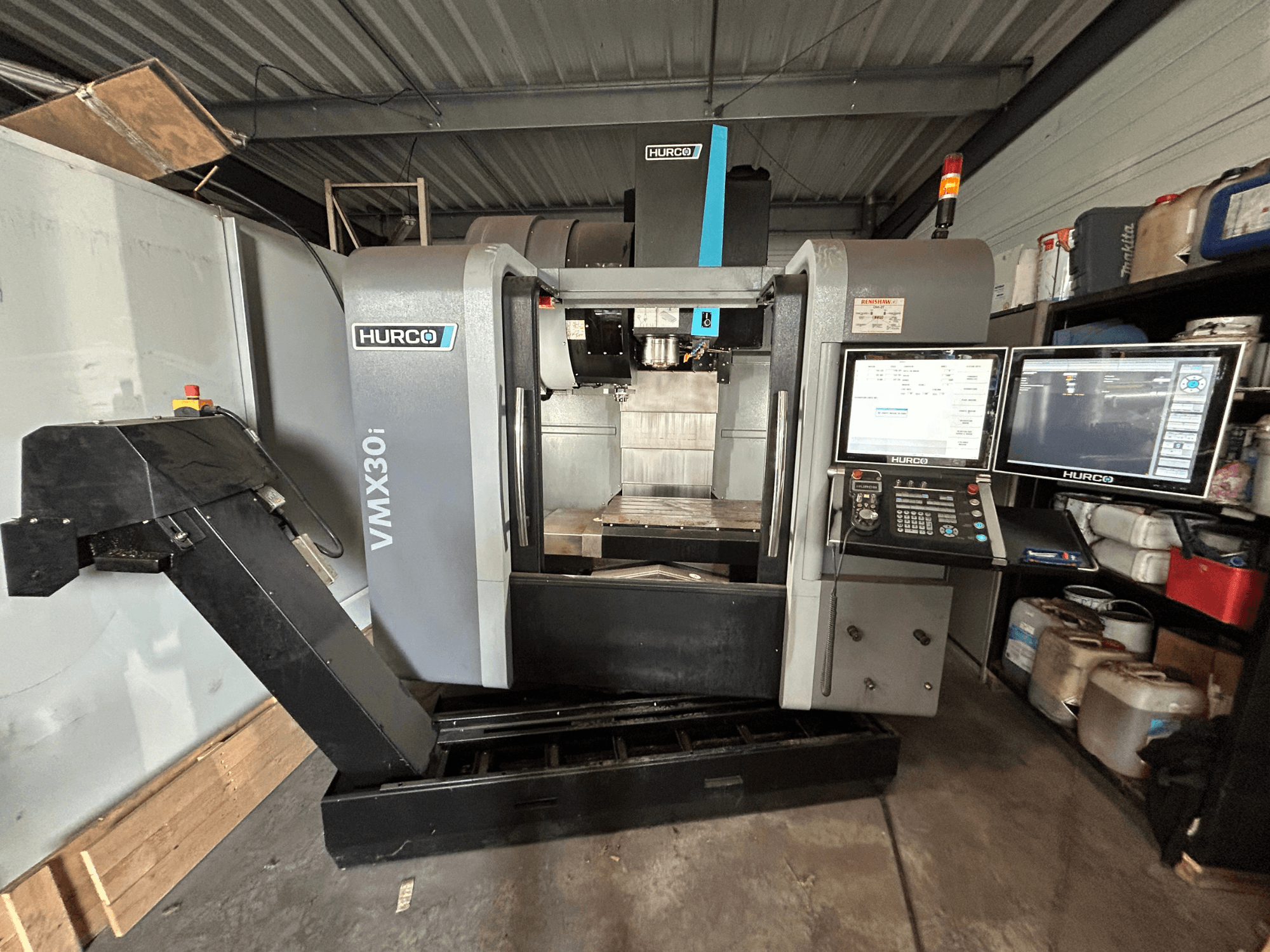 Centre d'usinage vertical Hurco VMX30i, vue de face avec deux moniteurs et commandes, présentant une zone de travail propre.