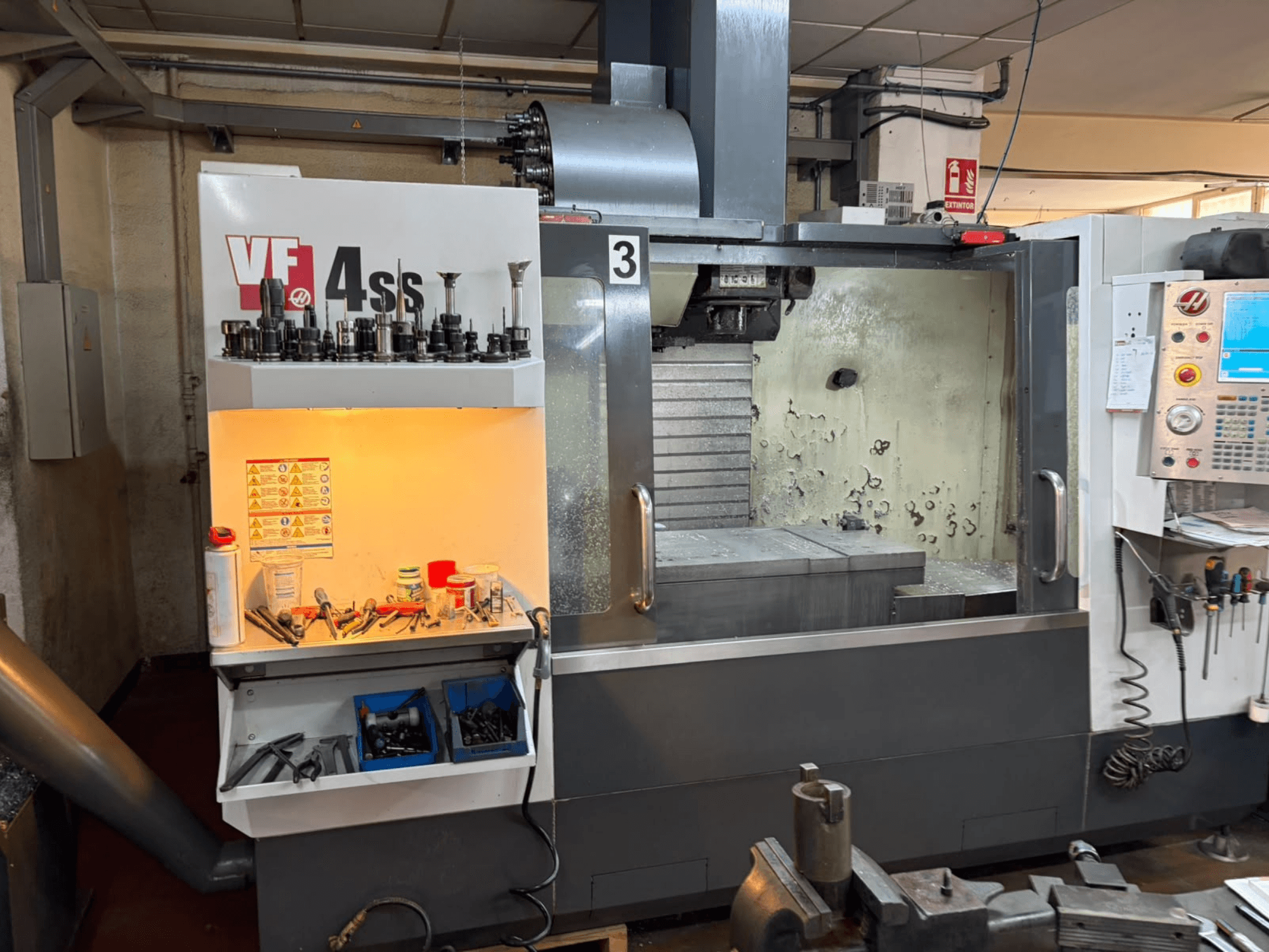 Centre d'usinage vertical HAAS VP 4SS, vue de face, présentant le magasin d'outils, le panneau de commande et la zone de travail visible avec les détails de l'usinage.