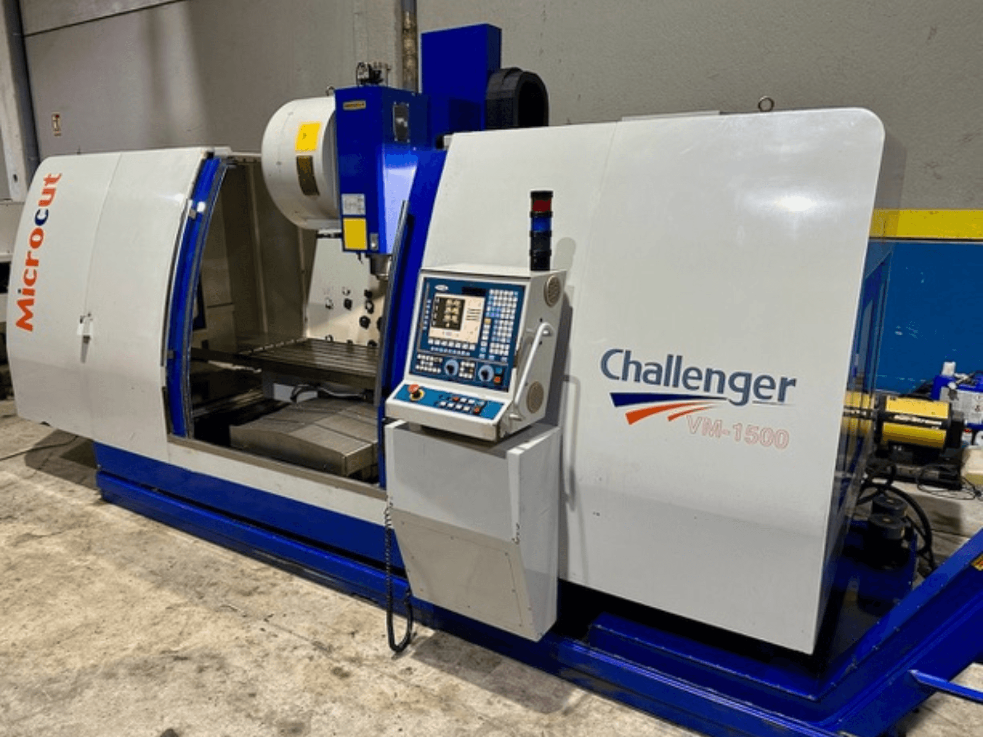 Machine CNC Microcut Challenger VM-1500, vue de face, comprenant un panneau de commande, un espace de travail et une base bleue.