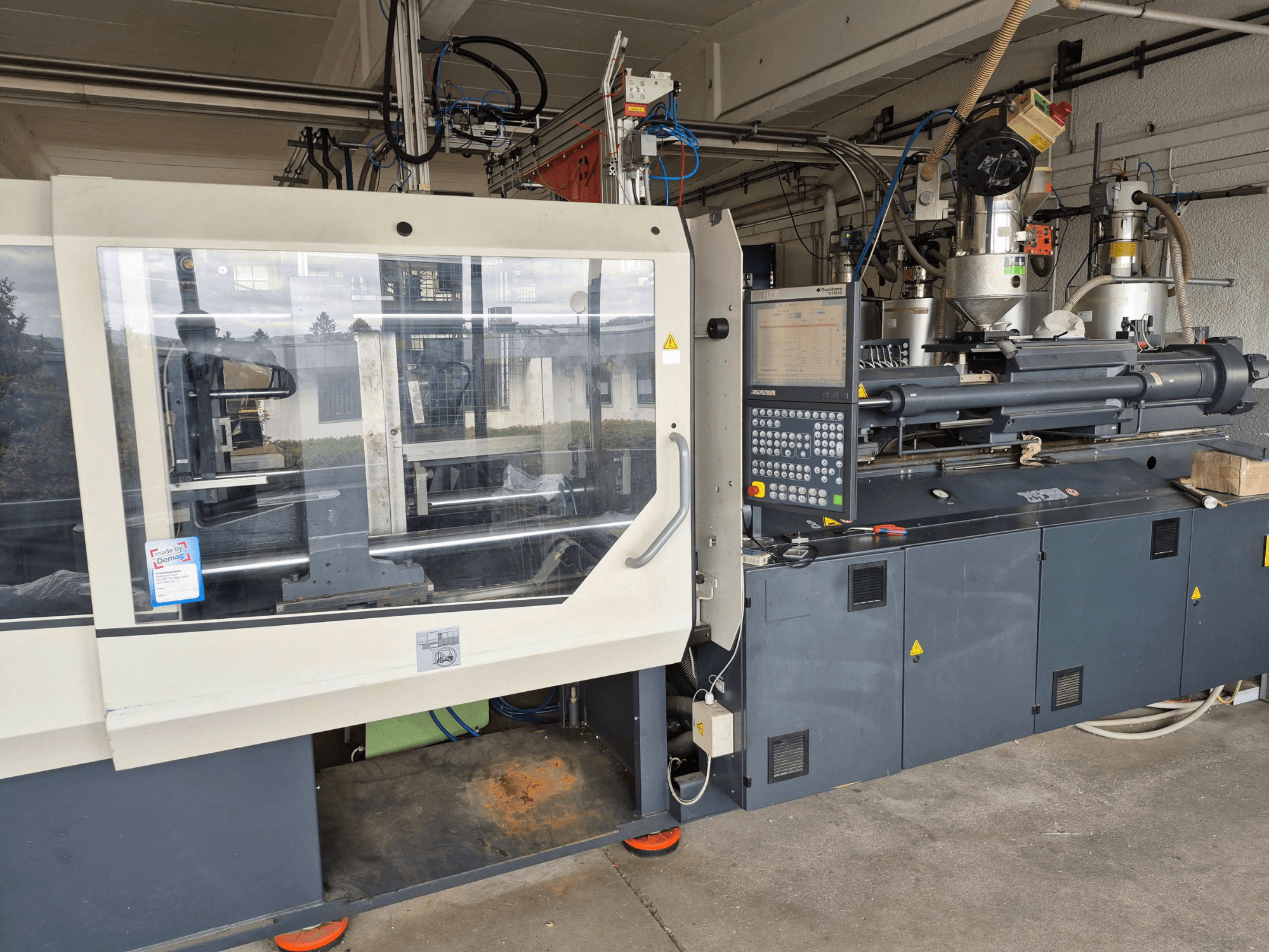 Machine de moulage par injection hydraulique, SUMITOMO SHI DEMAG Systec 210/580-1450, vue de face avec le panneau de commande et les composants visibles.