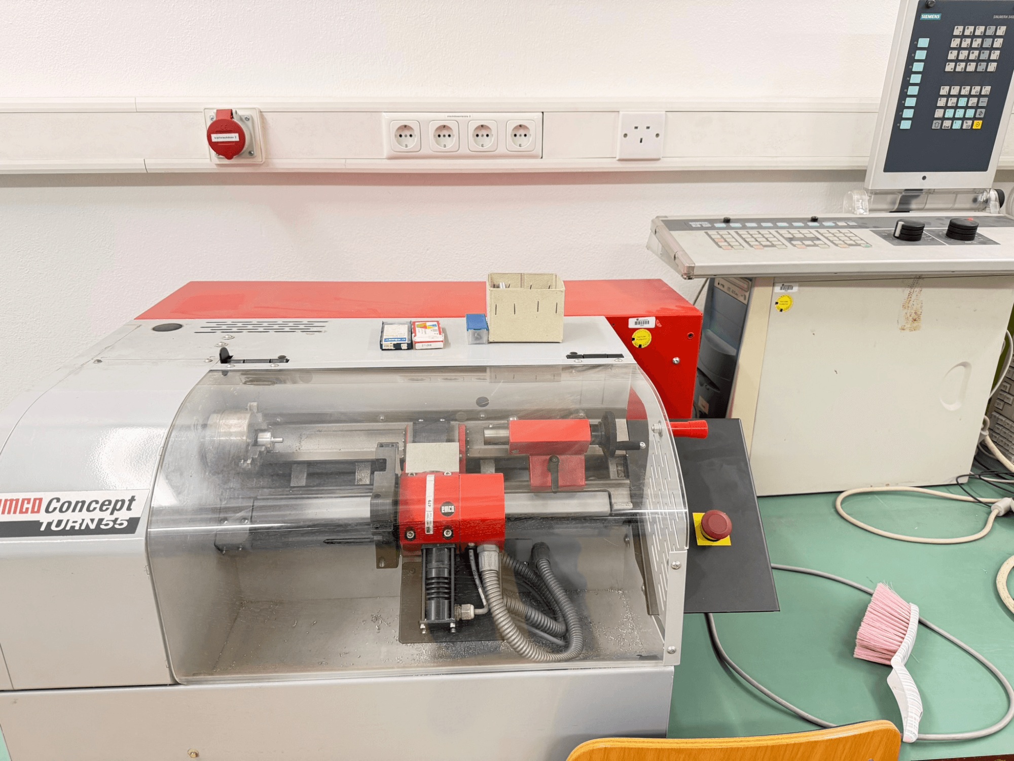 Tour horizontal EMCO Concept Turn 55 avec extérieur rouge et gris, vue de face montrant les commandes et la zone de travail.