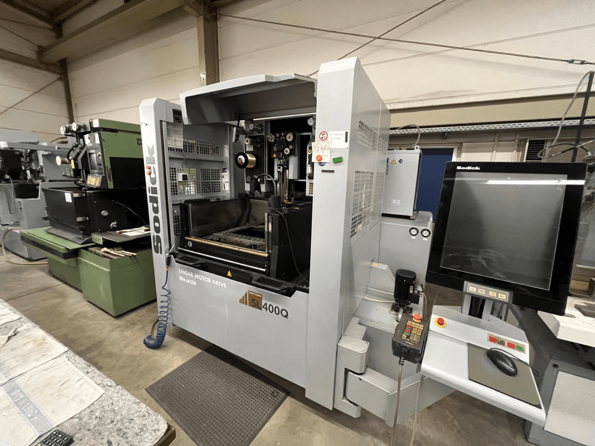 Machine CNC Sodick SL400Q à entraînement par moteur linéaire, vue de face avec panneau de commande numérique et écran dans un atelier.