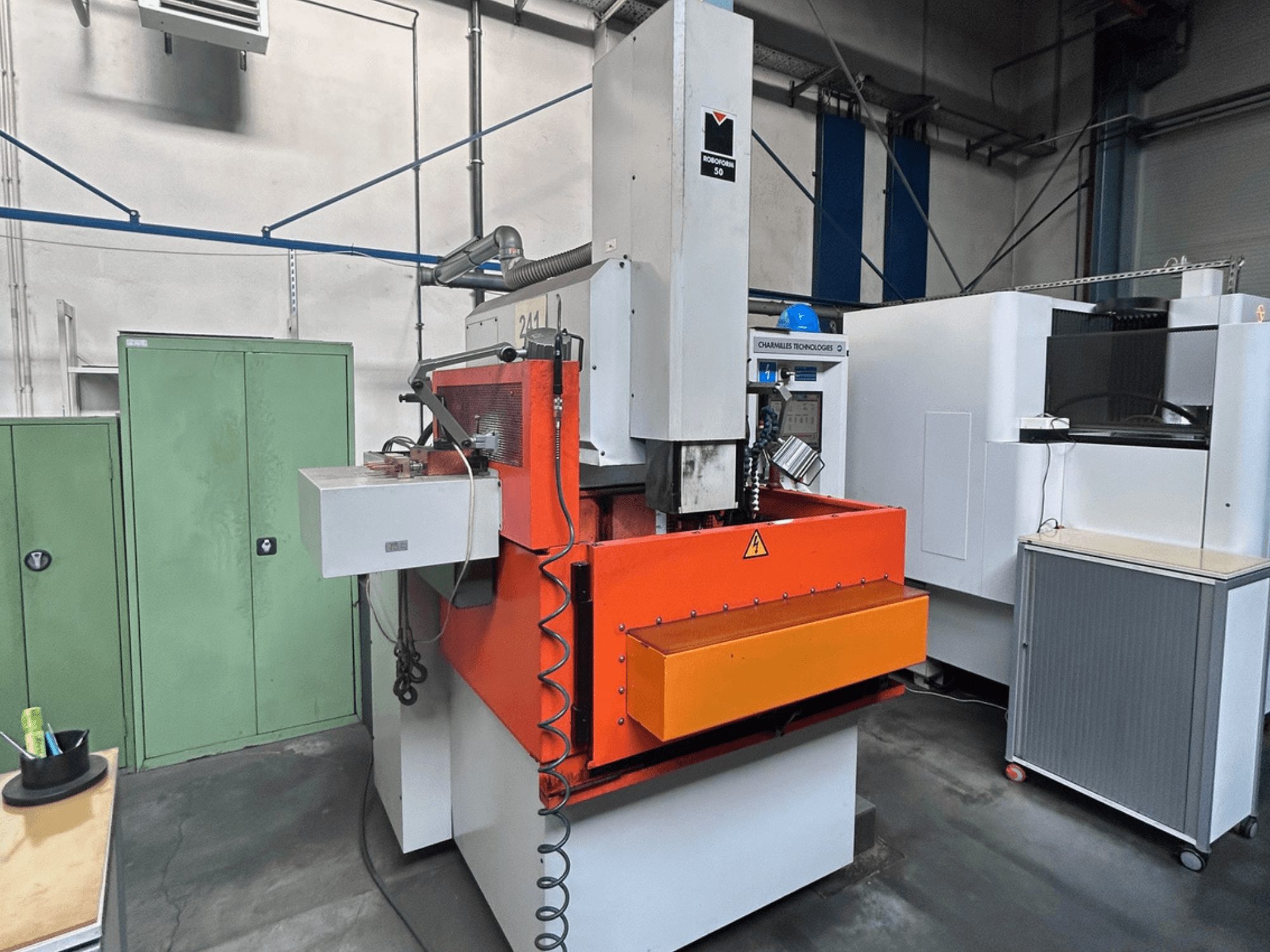 Vue avant de la machine d'électroérosion par enfonçage CHARMILLES ROBOFORM 50 avec le panneau orange, l'interface de commande et les équipements environnants.