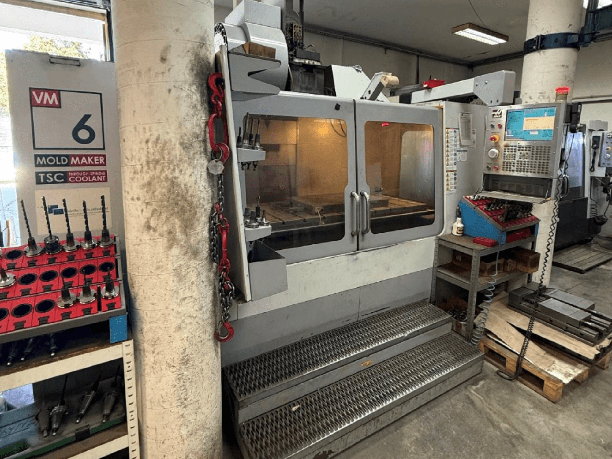 Centre d'usinage vertical HAAS VM-6 HE, vue de face montrant les commandes, le système de refroidissement et le rangement des outils.