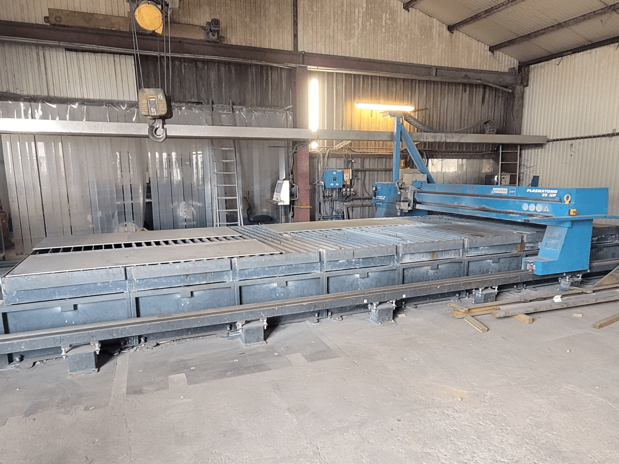 Machine de découpe plasma SAF Plasmatone 25Hp, vue de côté, montrant le banc de découpe et les composants opérationnels dans un environnement industriel.