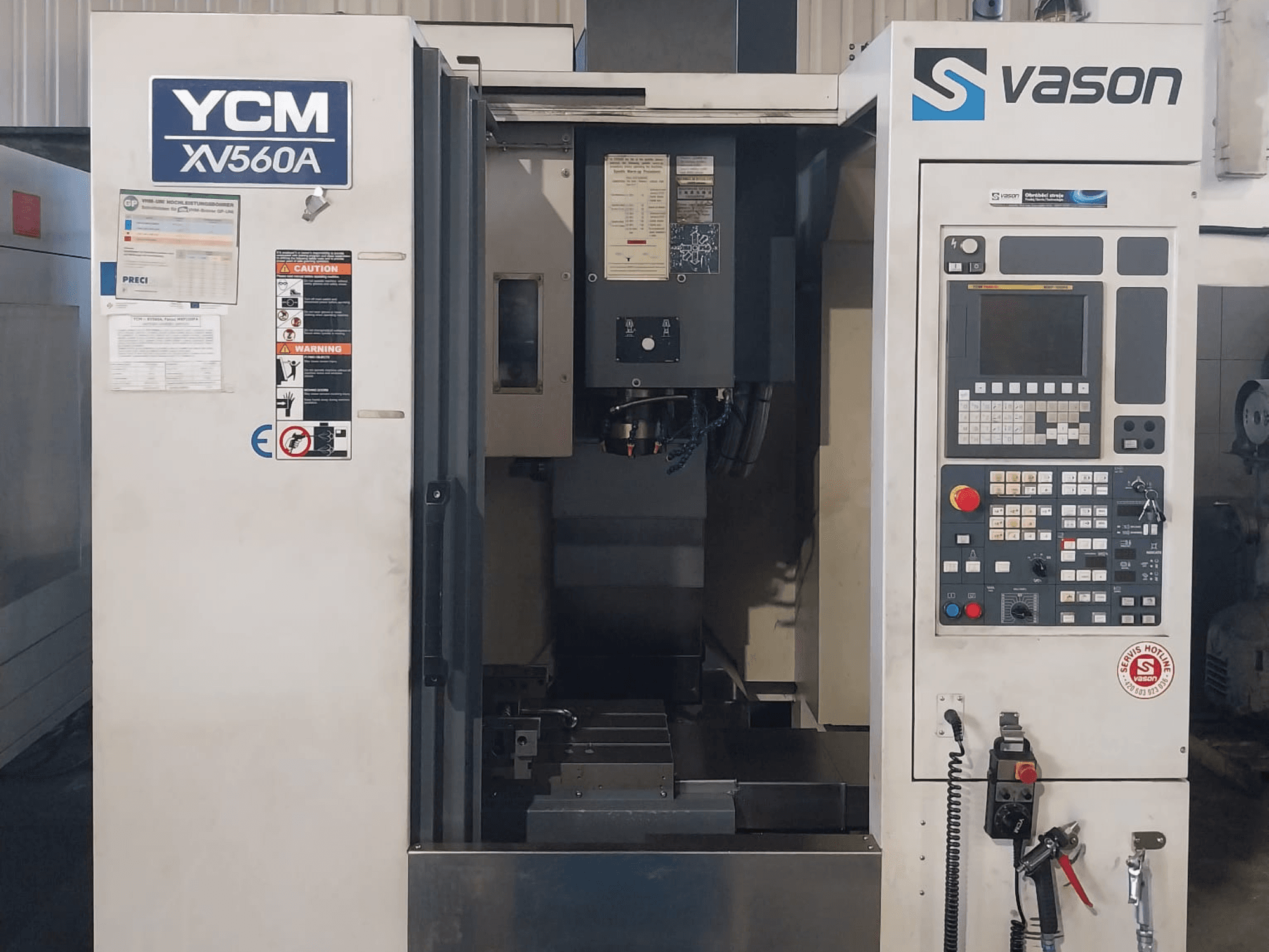 Vue de face du centre d'usinage vertical YCM XV 560A, avec le panneau de commande et la table de travail, les composants d'usinage étant visibles.
