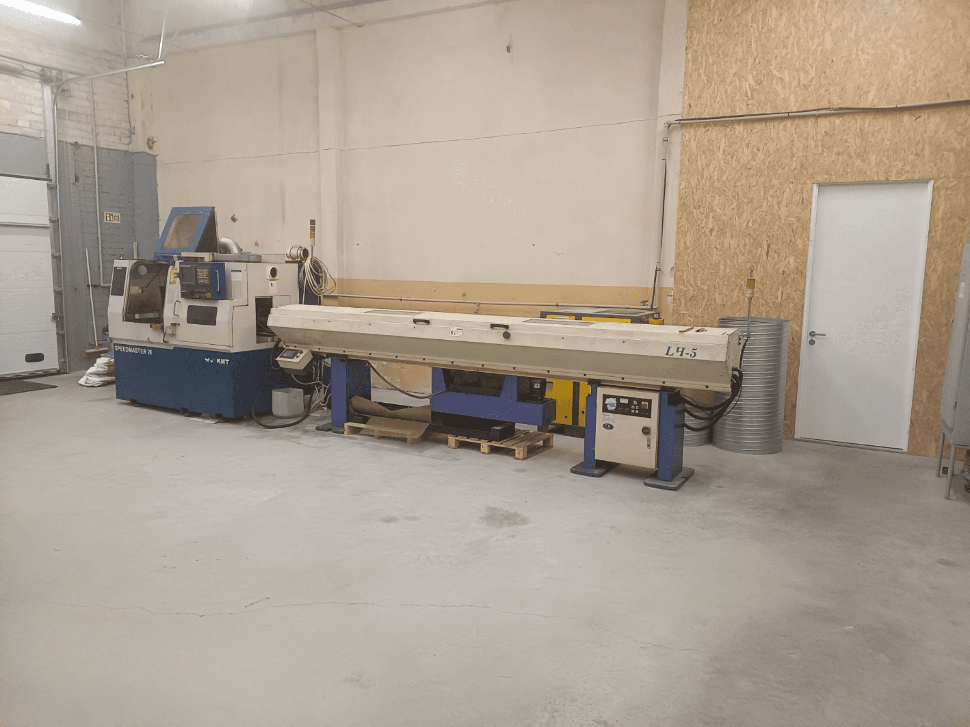 Atelier industriel équipé d'une machine KMT Speedmaster 34 et d'une L4.5, vue de face, avec les commandes et les machines visibles.