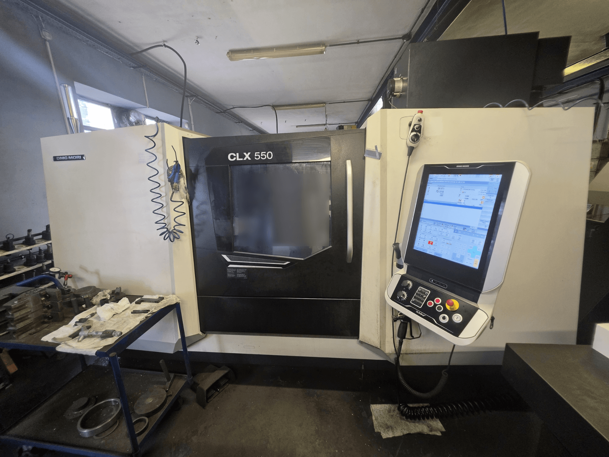 Tour horizontal DMG MORI CLX 550 V3, vue de face, montrant le panneau de commande et l'espace de travail avec les outils.