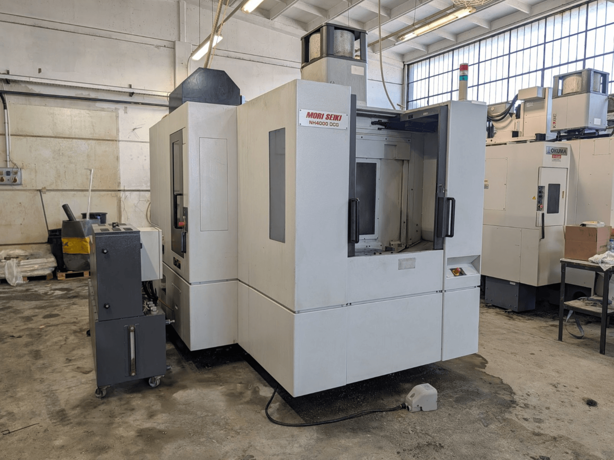Centre d'usinage horizontal MORI SEIKI NH 4000 DCG, vue de face, présentant le panneau de commande et la zone de travail, finition grise et blanche.